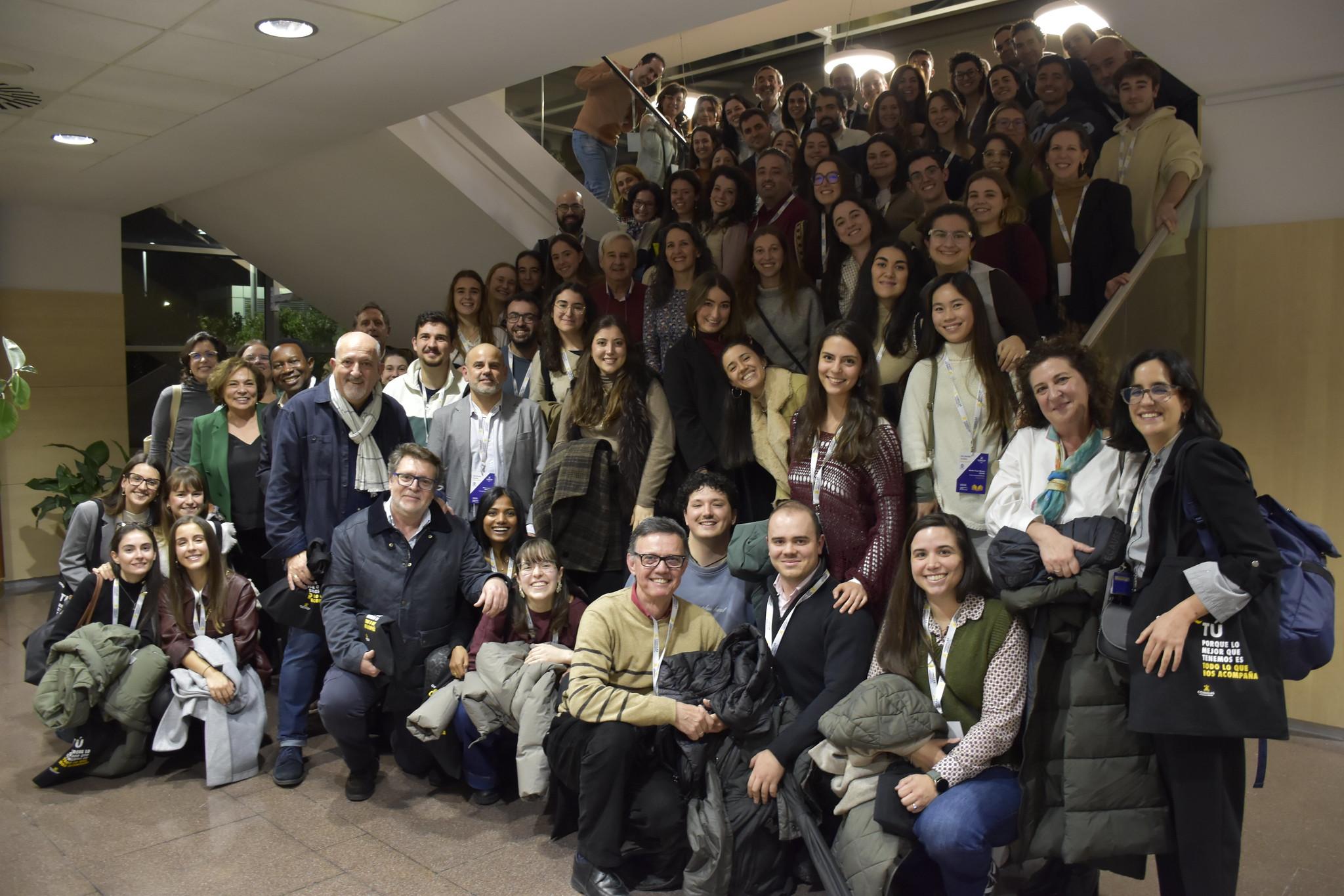 Un grupo grande de personas sonrientes se reúne en una escalera en un ambiente acogedor.