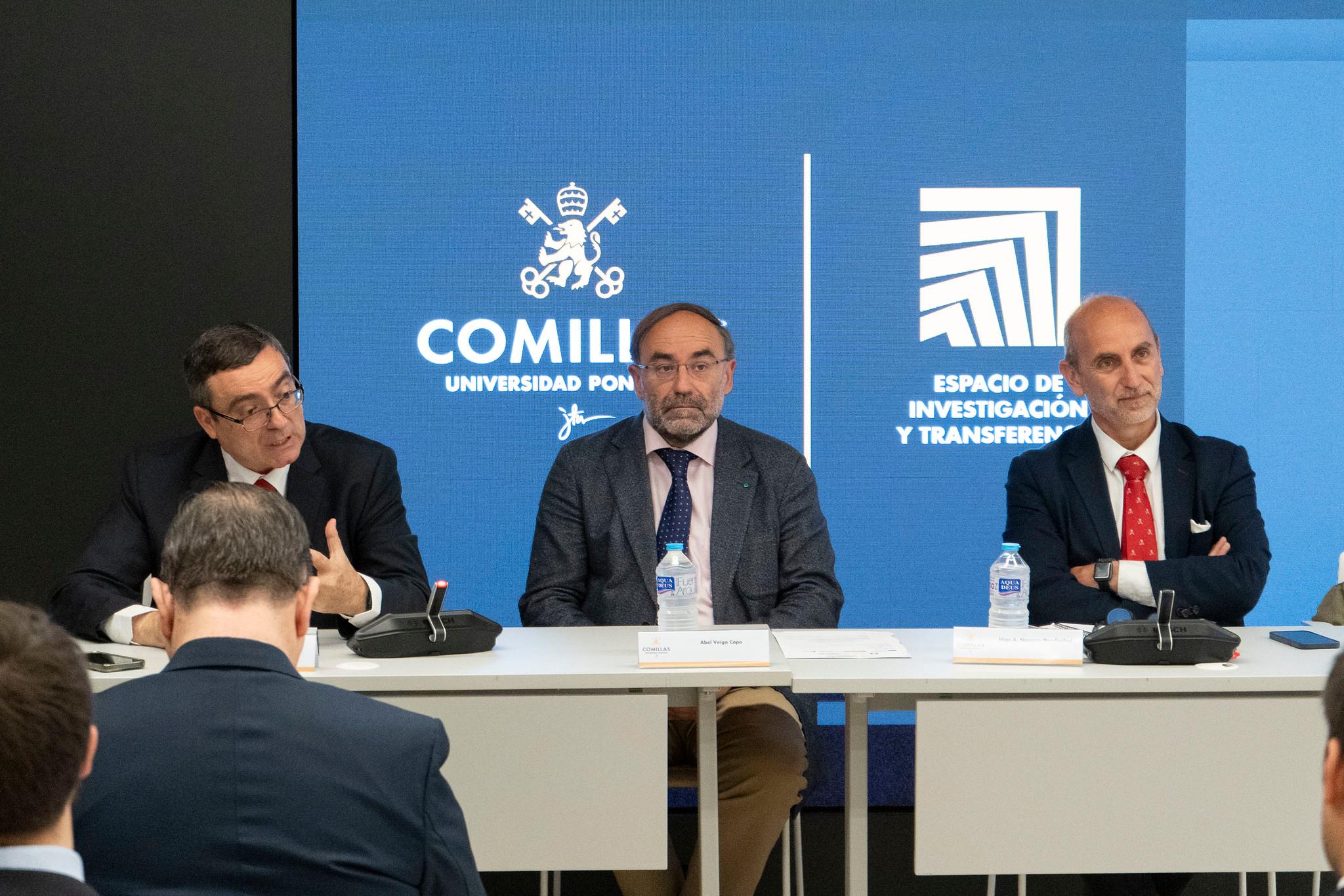 Una mesa redonda con tres ponentes discutiendo en un evento académico.