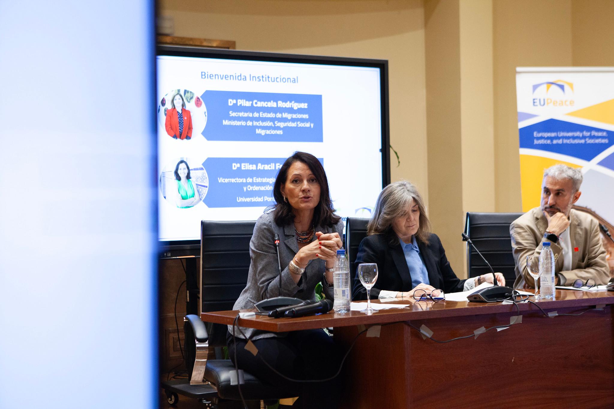 Una mesa redonda con tres personas discutiendo en un evento académico.