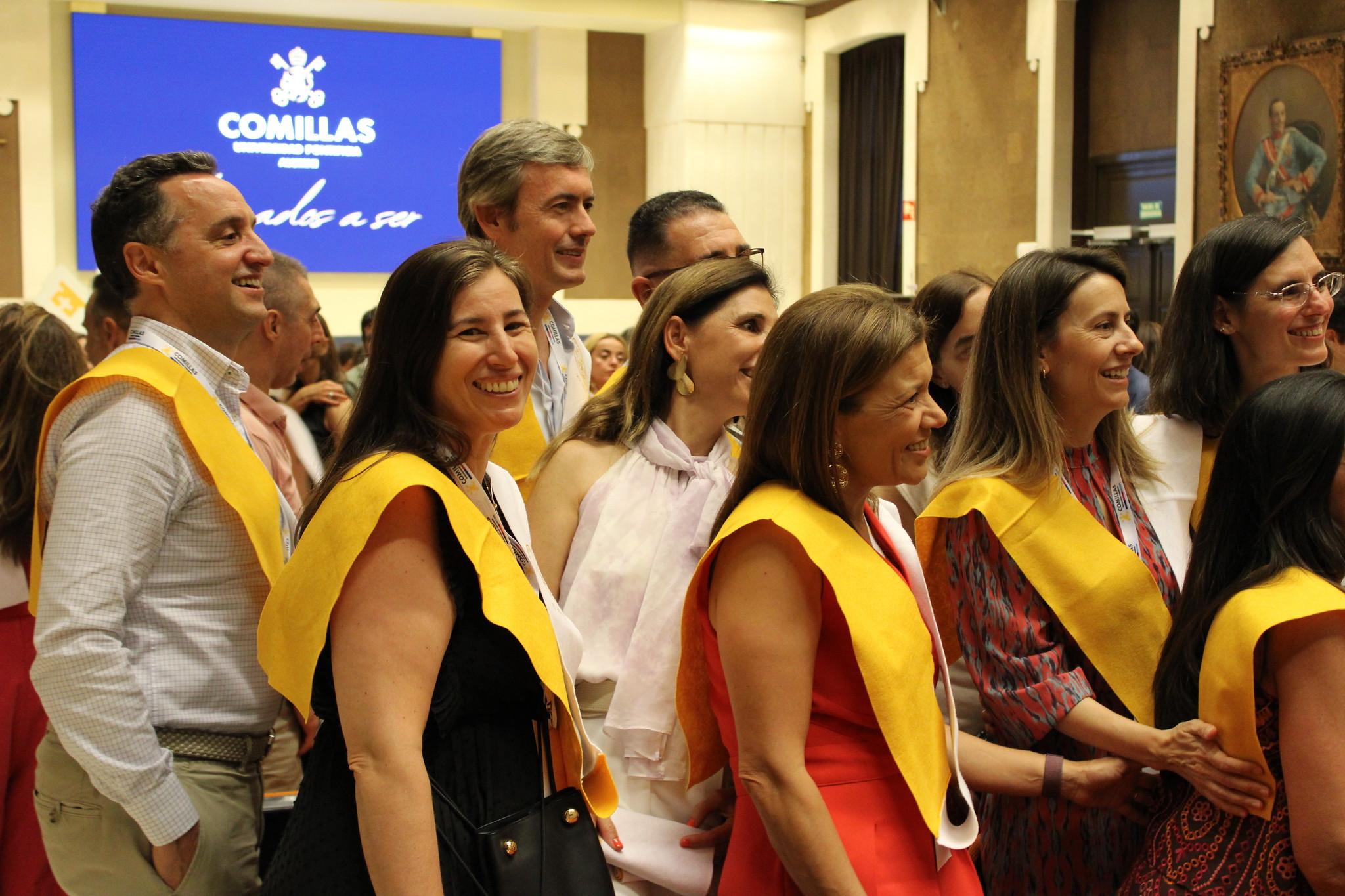 Grupo de personas sonriendo y celebrando en un evento social con cintas amarillas.