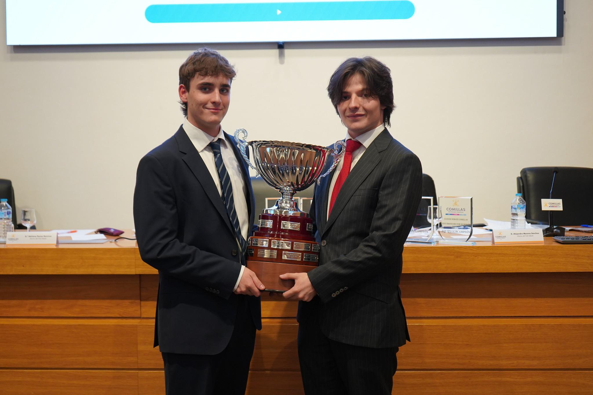 Dos jóvenes sosteniendo un trofeo en un evento formal.
