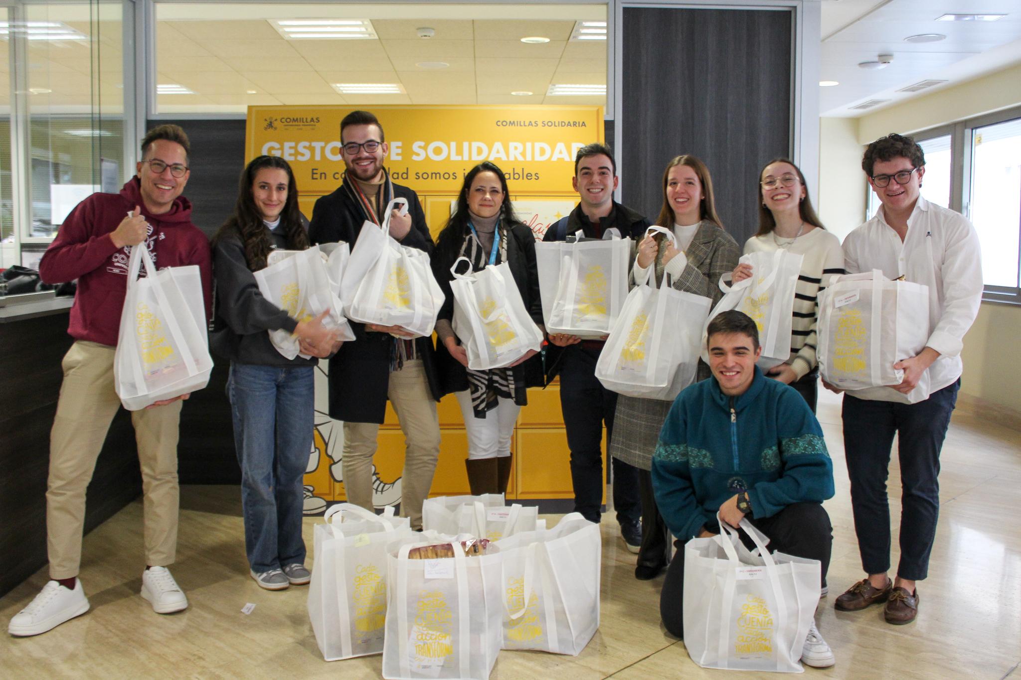 Un grupo de personas sonriendo en un recinto cerrado, sosteniendo bolsas de tela con un logo visible.