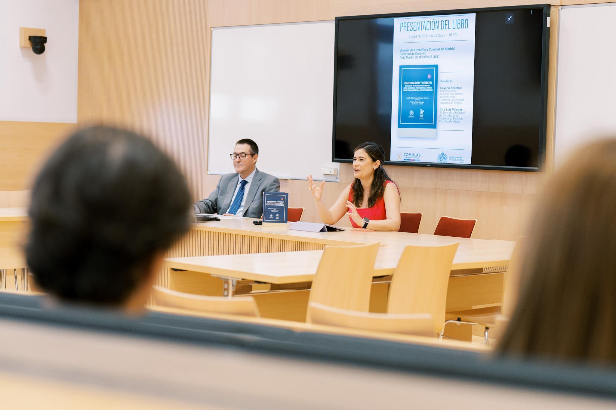 Una presentación de un libro en un aula con dos oradores y un público presente.