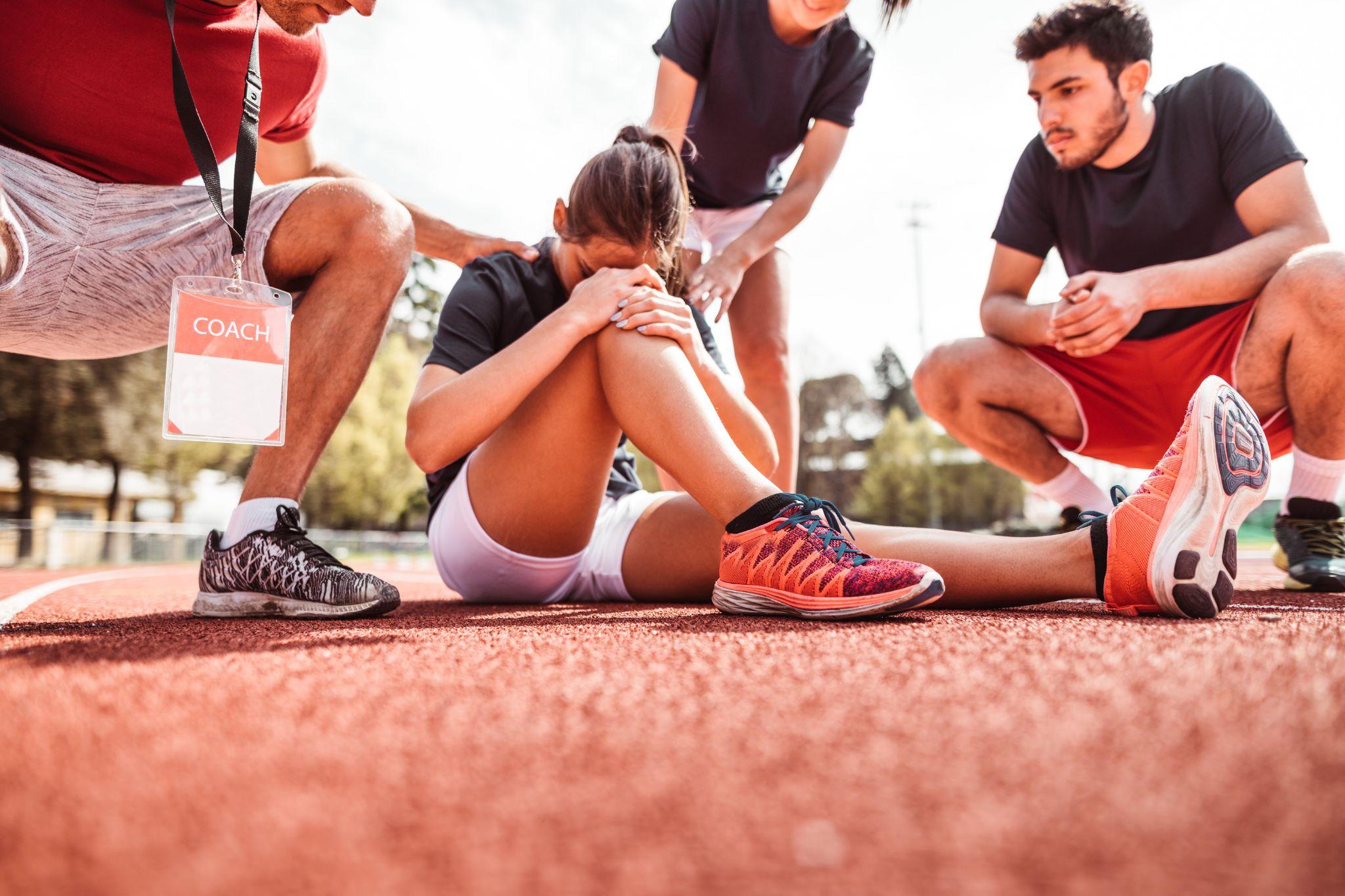 Un grupo de personas ayuda a una atleta que parece haber sufrido una lesión en la pista de atletismo.