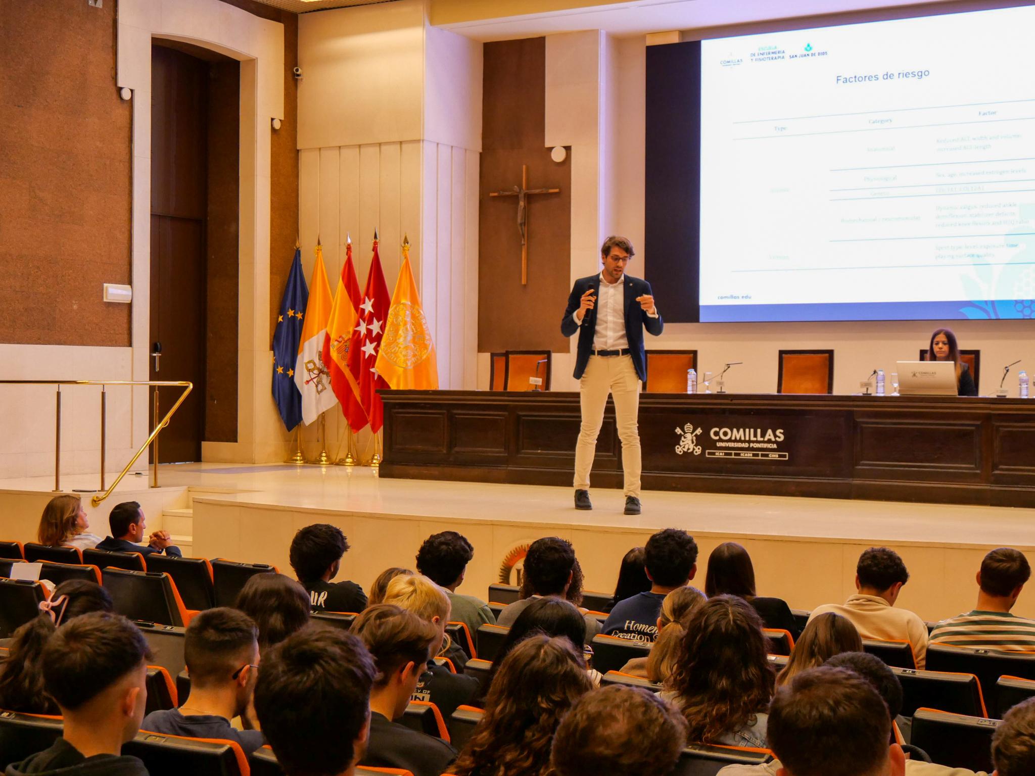 Un ponente da una charla frente a un auditorio lleno de estudiantes en un evento educativo.