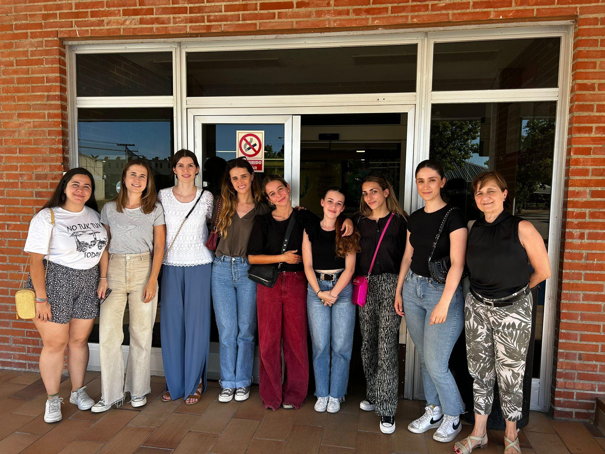 A group of eight women standing in front of a building entrance.