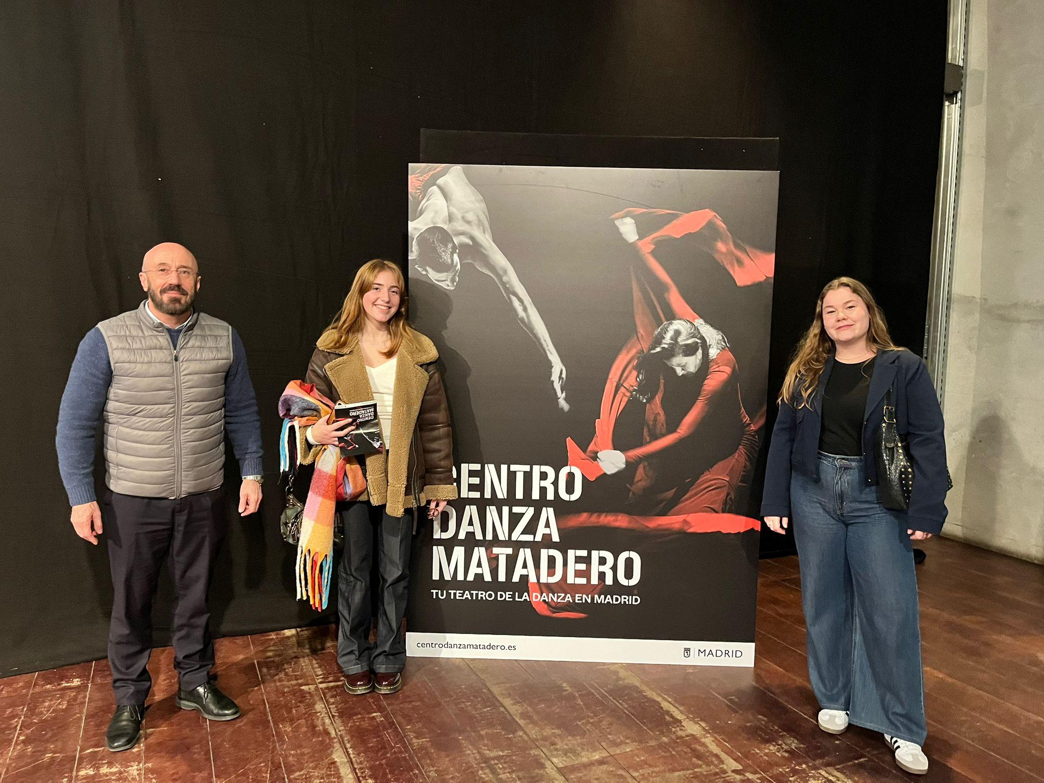 Tres personas posan frente a un cartel del Centro Danza Matadero en Madrid.