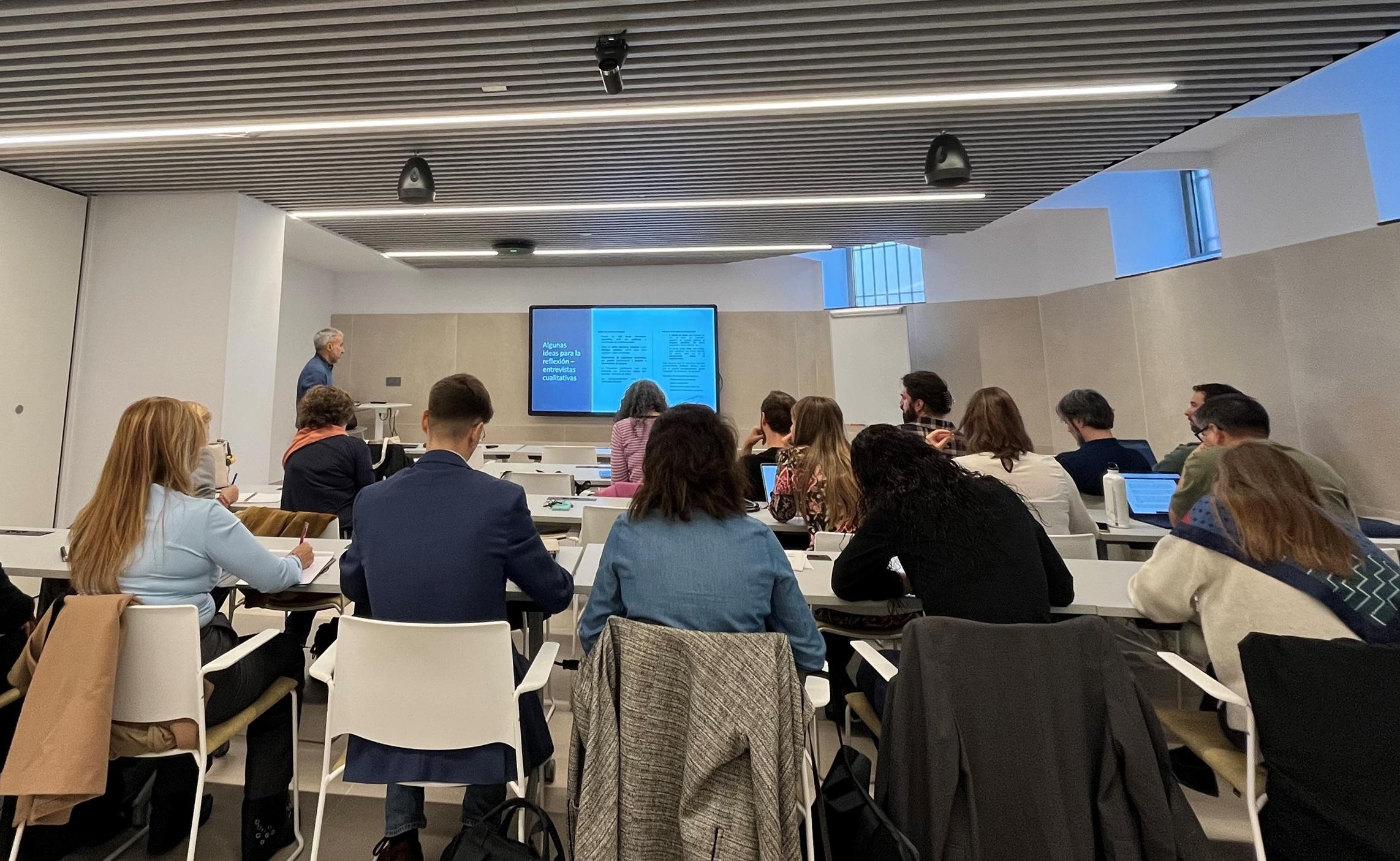 Un grupo de personas asiste a una presentación en un aula moderna con proyector.
