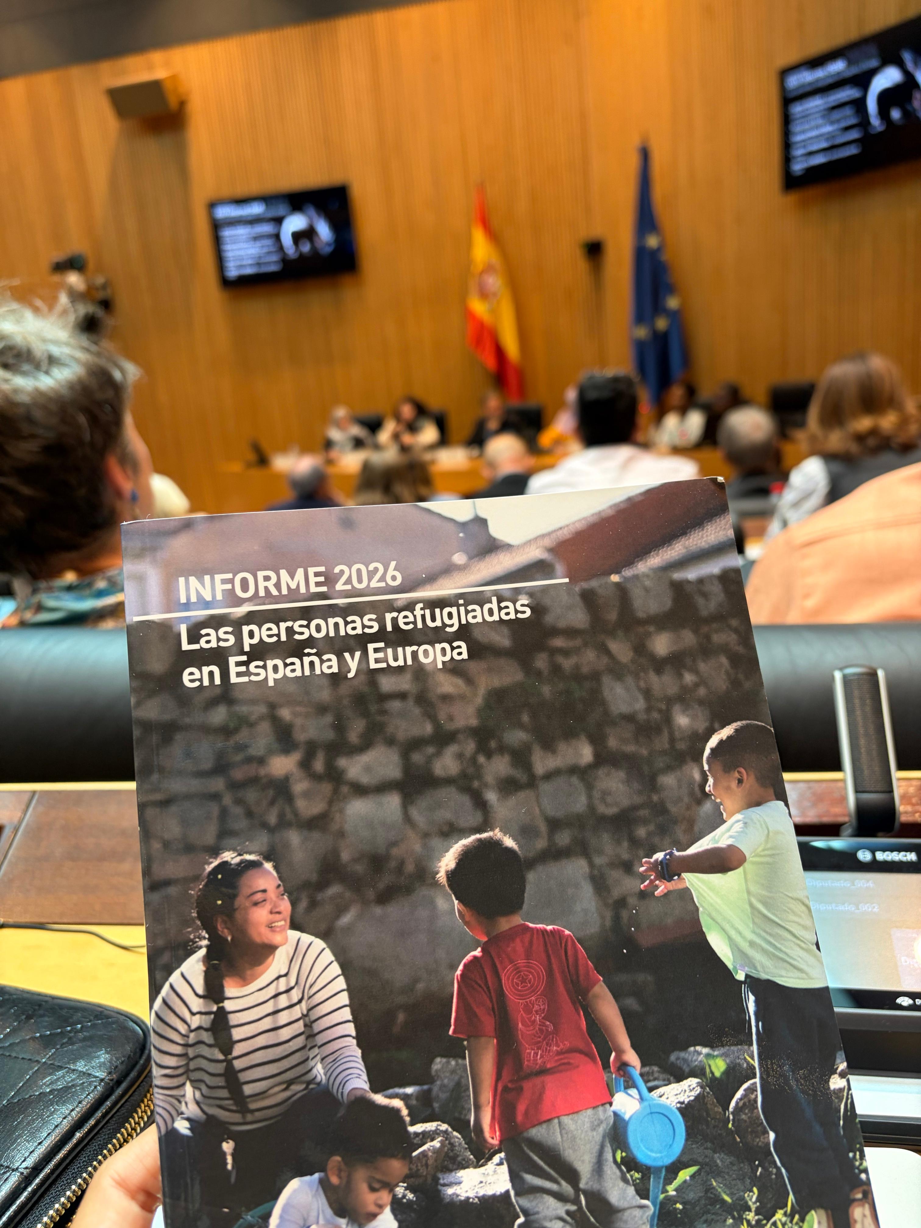 La imagen muestra una presentación en un evento sobre el informe 2026 acerca de las personas refugiadas en España y Europa.