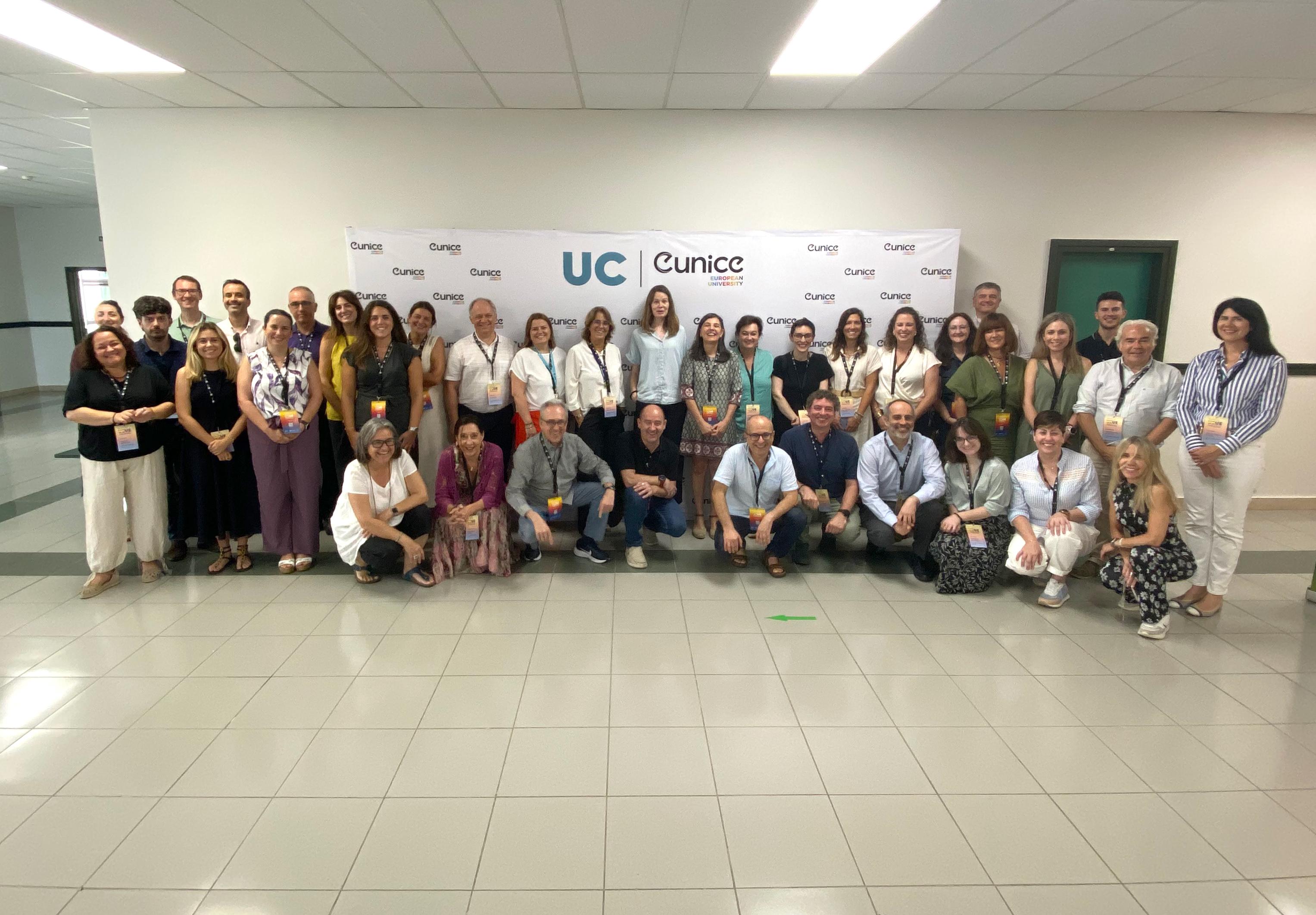 Un grupo de personas posando frente a un cartel de la UC y Cunicc en un salón amplio.