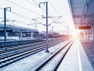 Sunrise view over a railway station with multiple tracks and a platform, in a cool blue tone.