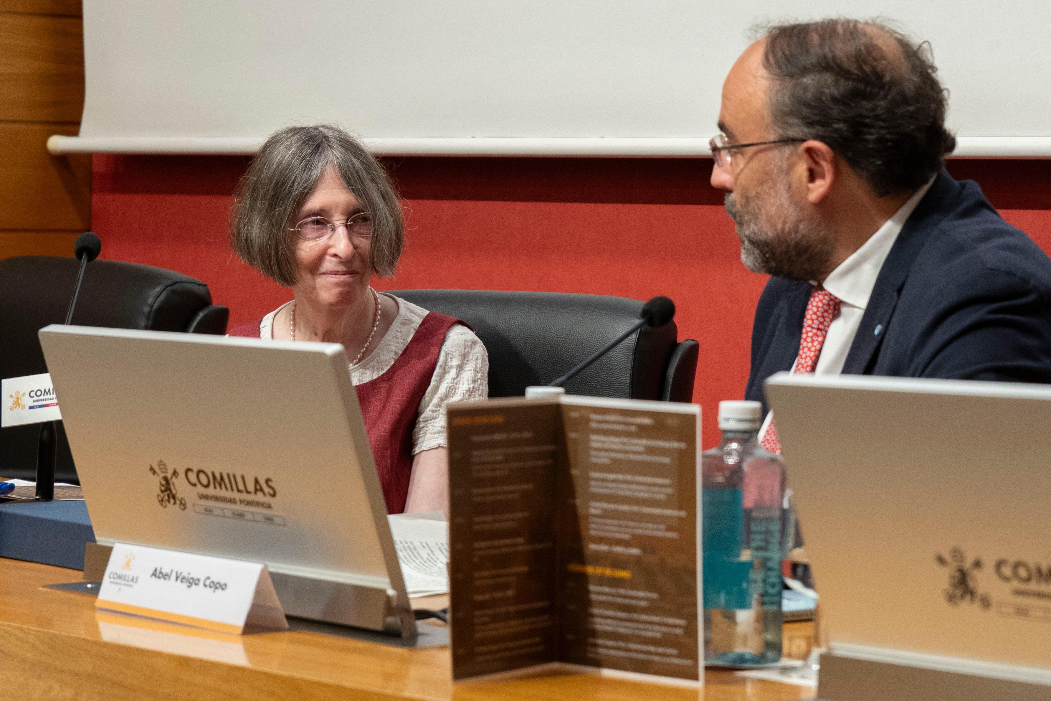 Una mujer y un hombre conversan en un evento académico en la Universidad Comillas.