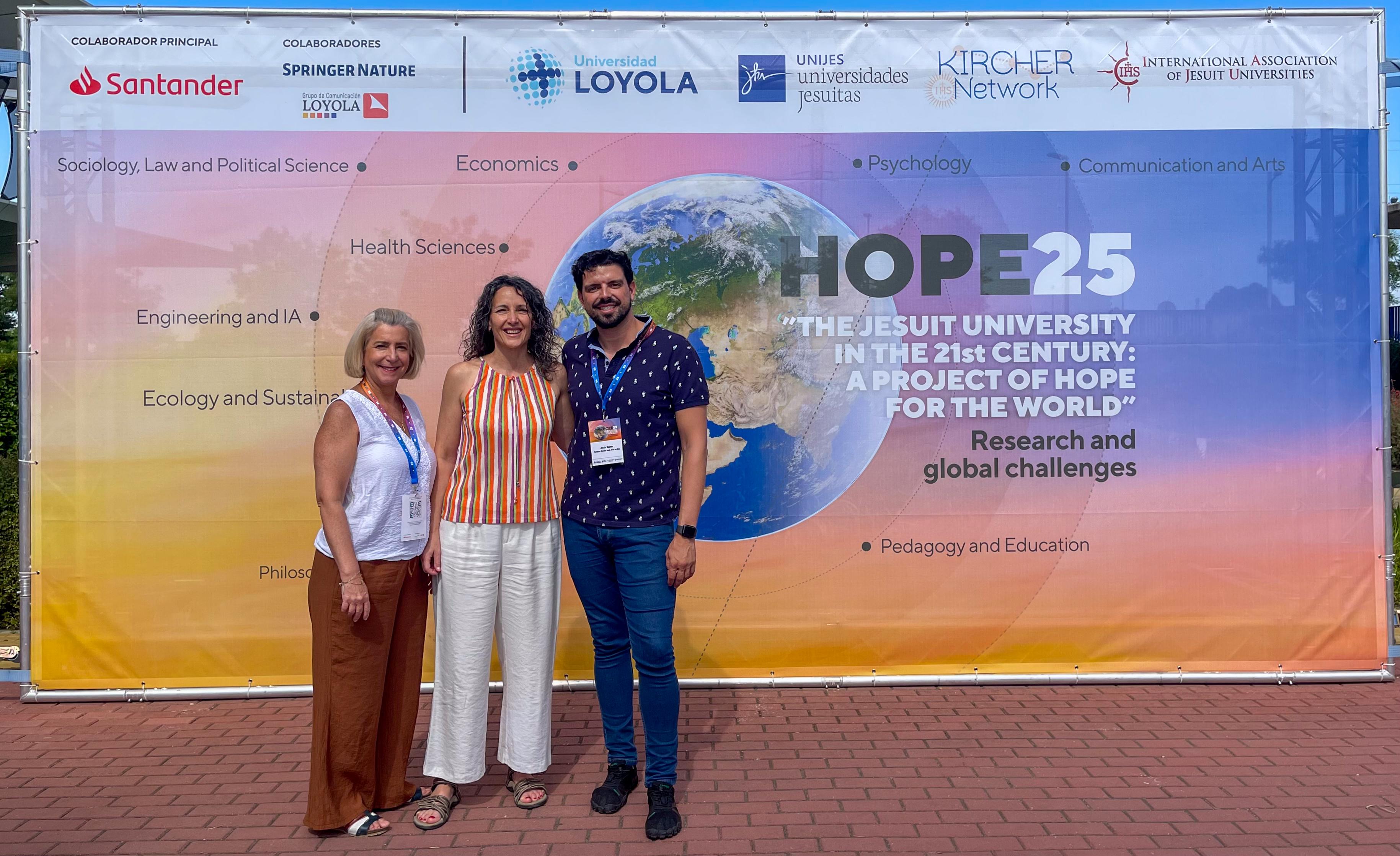 Tres personas posan frente a un fondo con el logo del evento HOPE25 sobre desafíos globales.