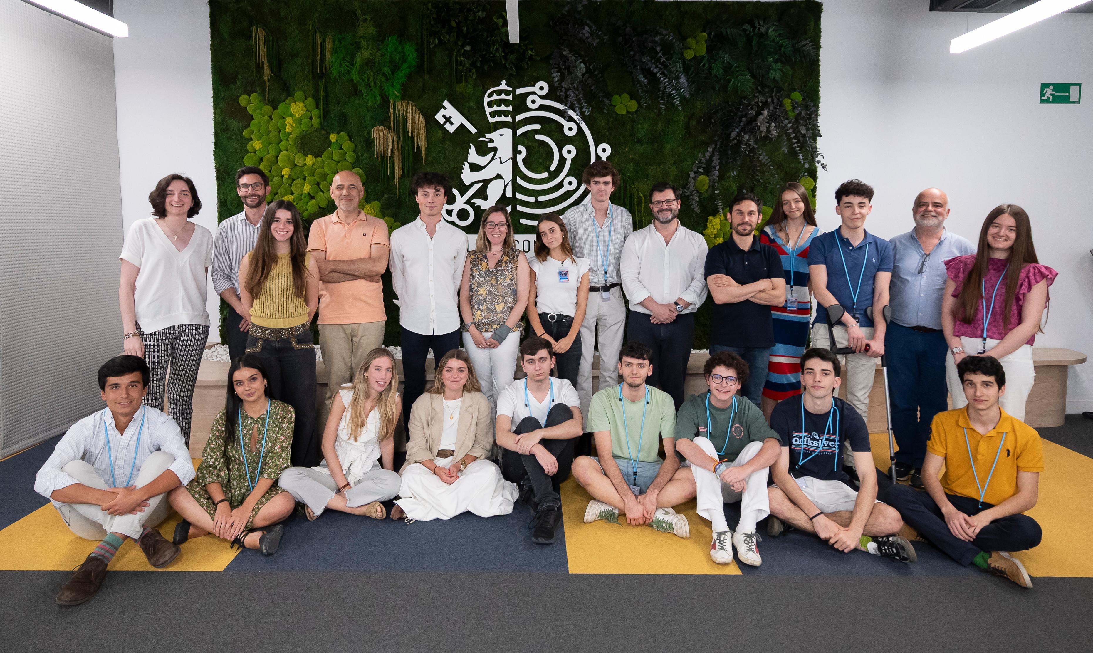 Grupo de personas posando en un ambiente interior con vegetación y un fondo decorativo.