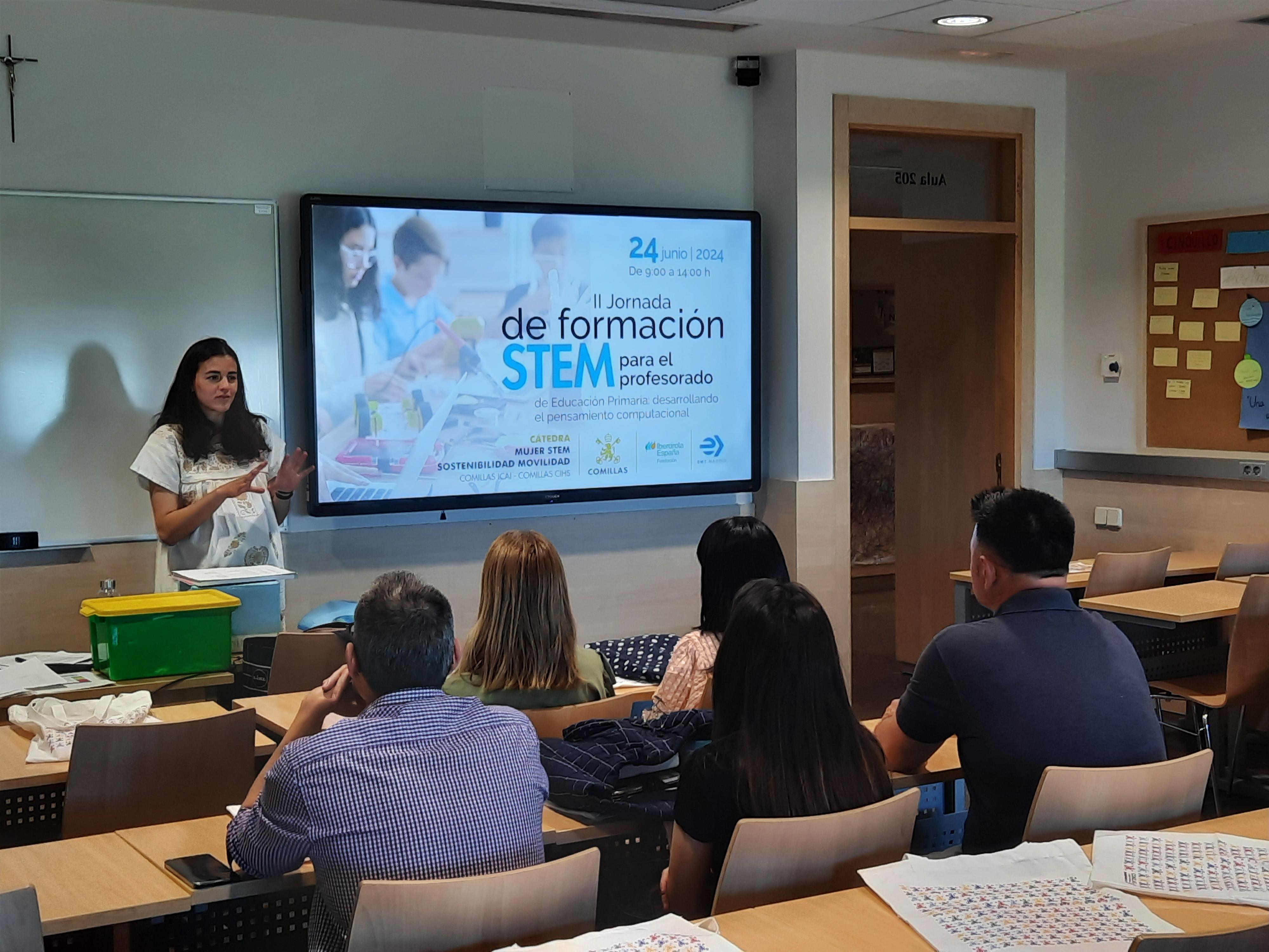 A woman presenting at a STEM education workshop in a classroom with attentive adult audience.