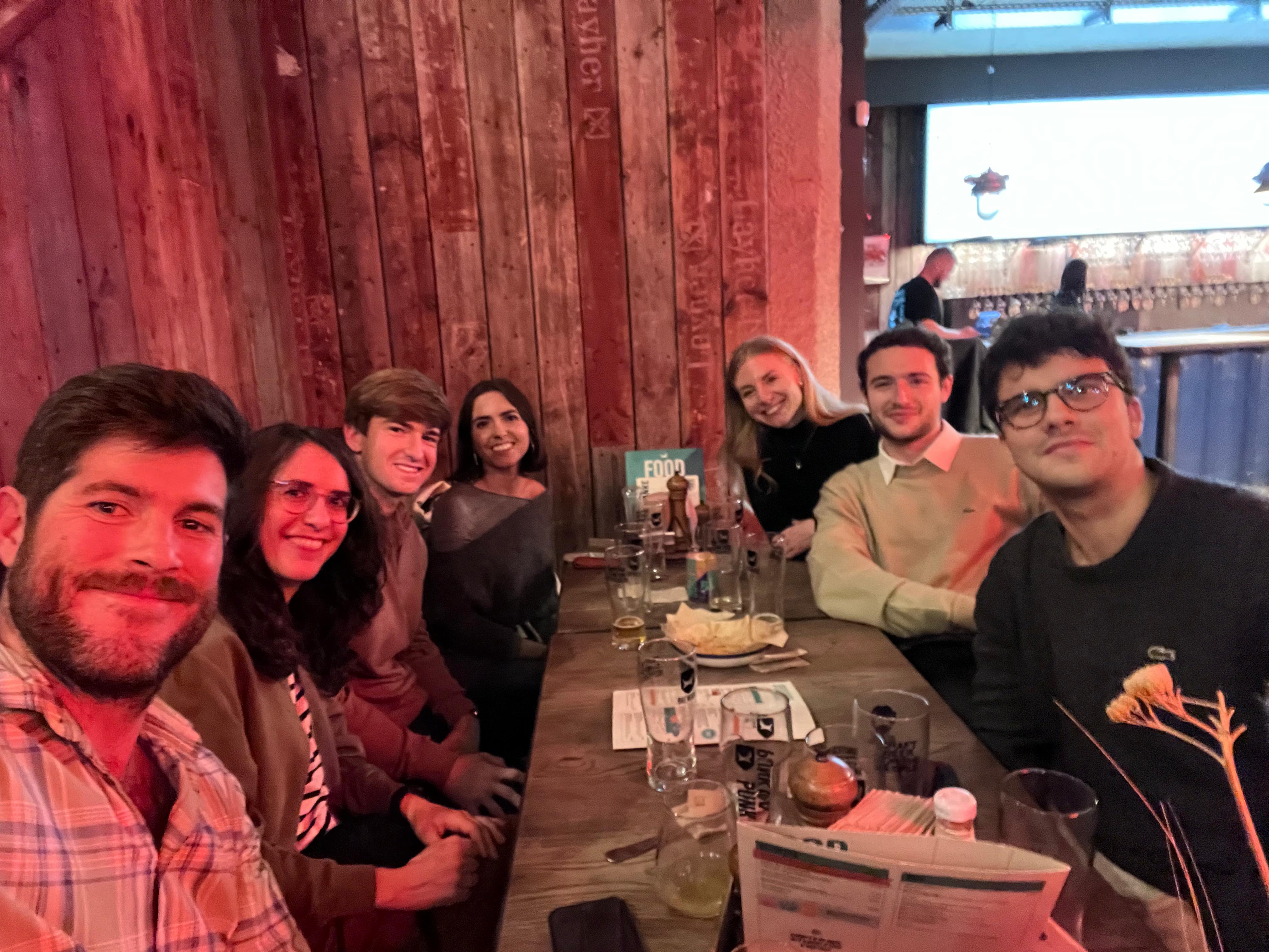 Un grupo de amigos sonríen mientras disfrutan de una cena juntos en un restaurante con ambiente acogedor.