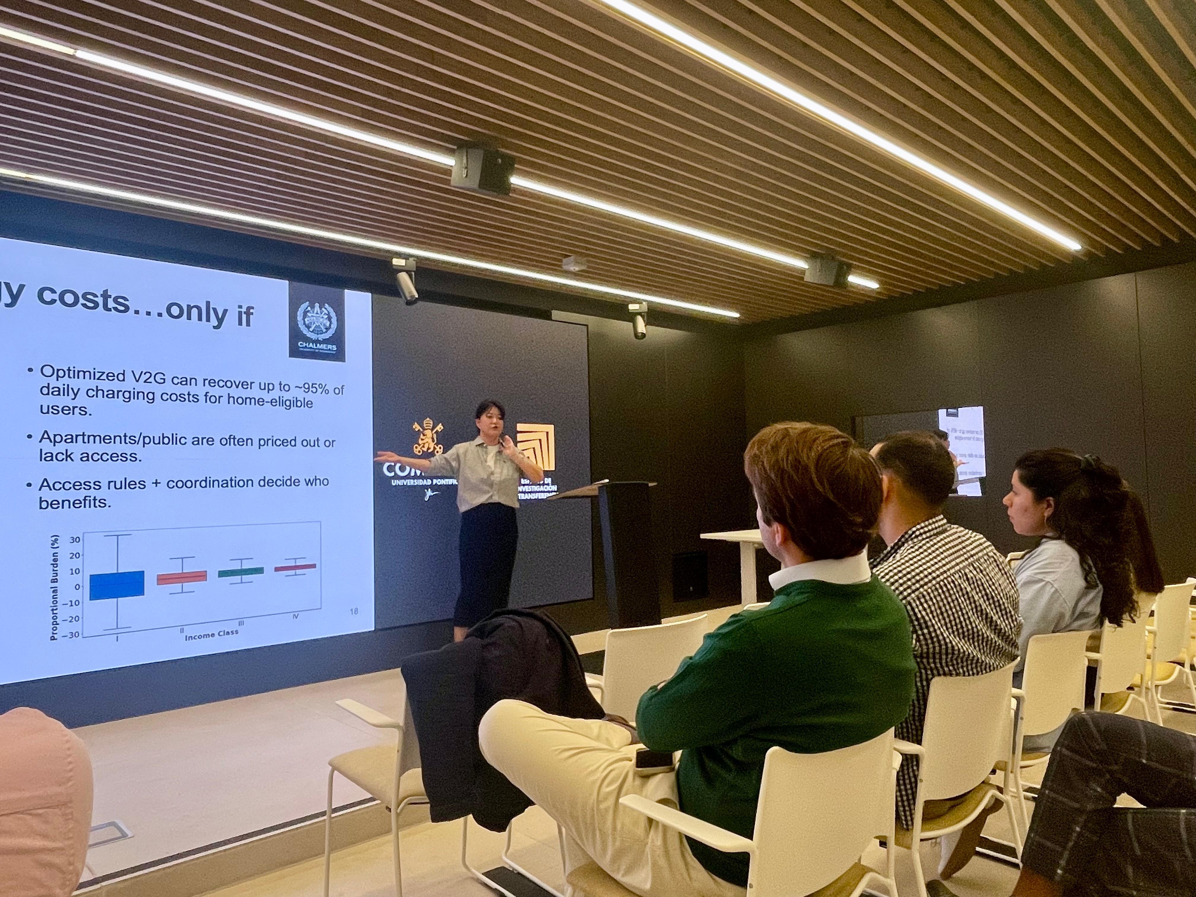 Una presentadora expone un gráfico en una sala de conferencias ante un público atento.