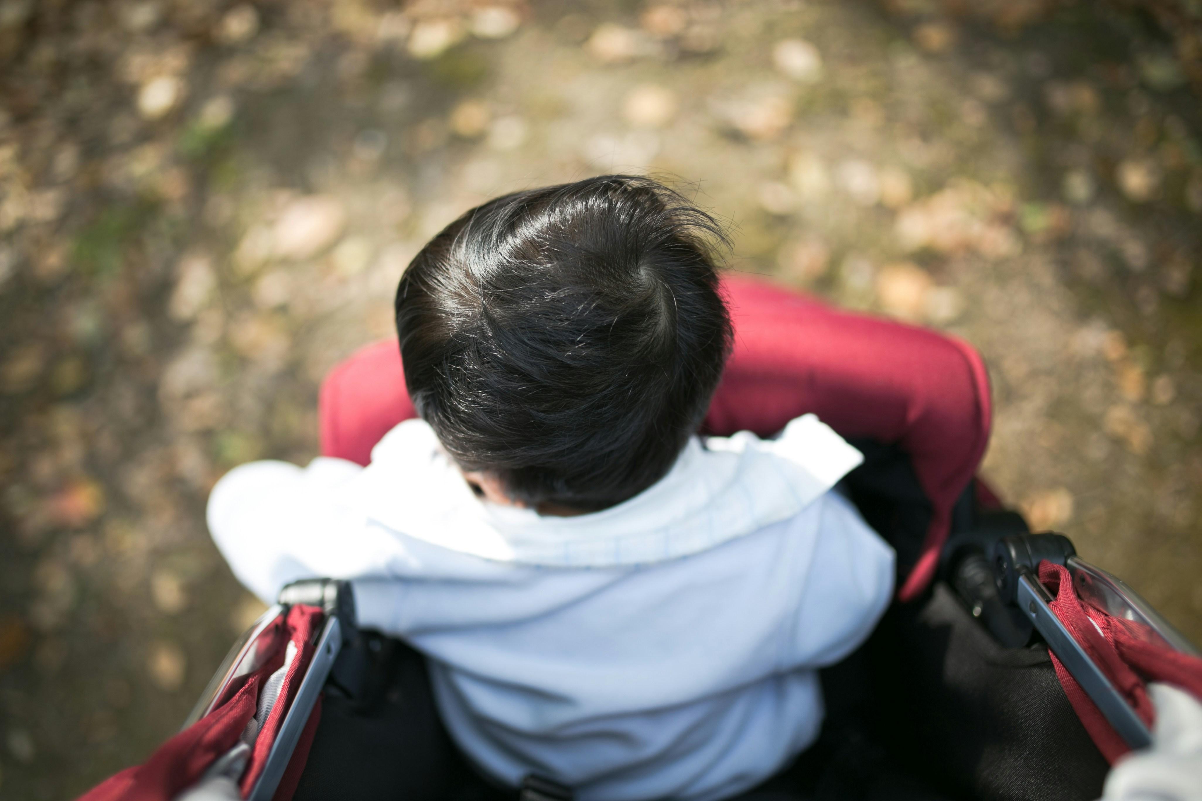 Un niño pequeño sentado en un carrito de paseo, visto desde arriba.