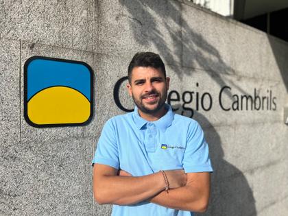 A man in a blue polo shirt standing in front of a sign that says 'Colegio Cambrils' with a logo next to it.