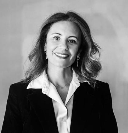 Retrato en blanco y negro de una mujer sonriente con cabello suelto y chaqueta negra.