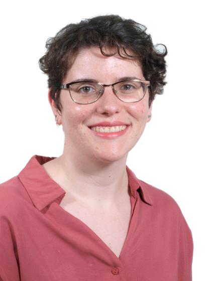 Retrato de una mujer sonriente con gafas y camisa roja sobre fondo blanco.