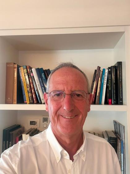 Un hombre sonriente posando frente a una estantería llena de libros.
