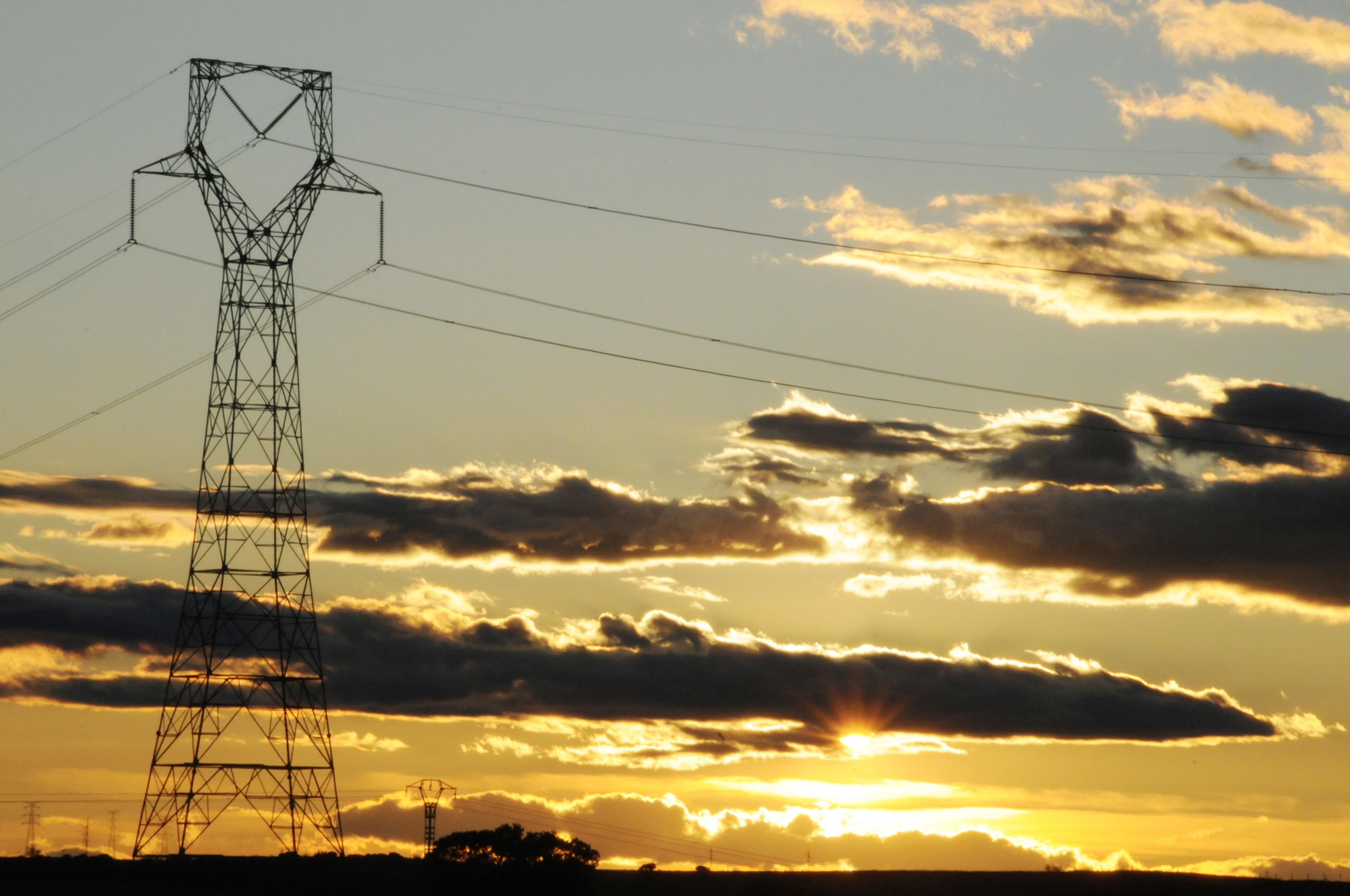 Sunset behind an electricity pylon with scattered clouds in the sky.