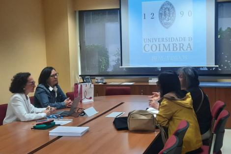 Reunión en la Universidad de Coimbra con varias personas discutiendo en una sala de conferencias.