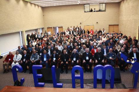 A large group of people seated in a conference hall with the letters 'CELAM' displayed in front.