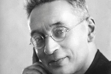 Black and white portrait of a smiling man wearing glasses.