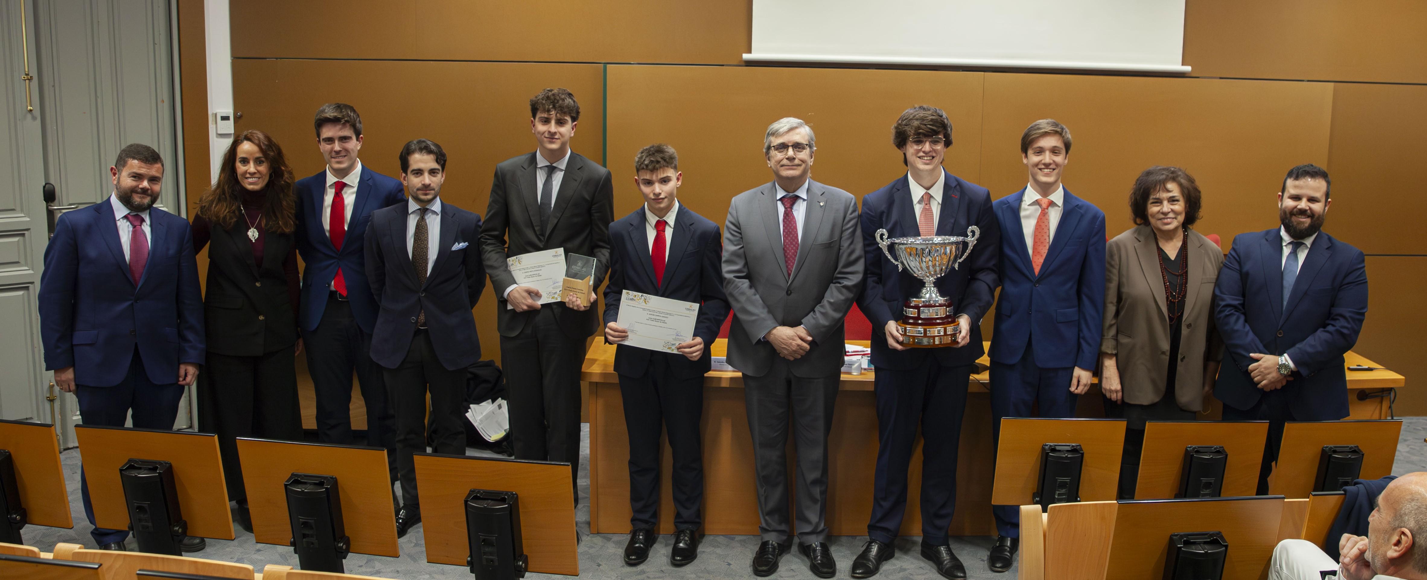 Grupo de personas posando en un auditorio, algunas sosteniendo premios y diplomas.