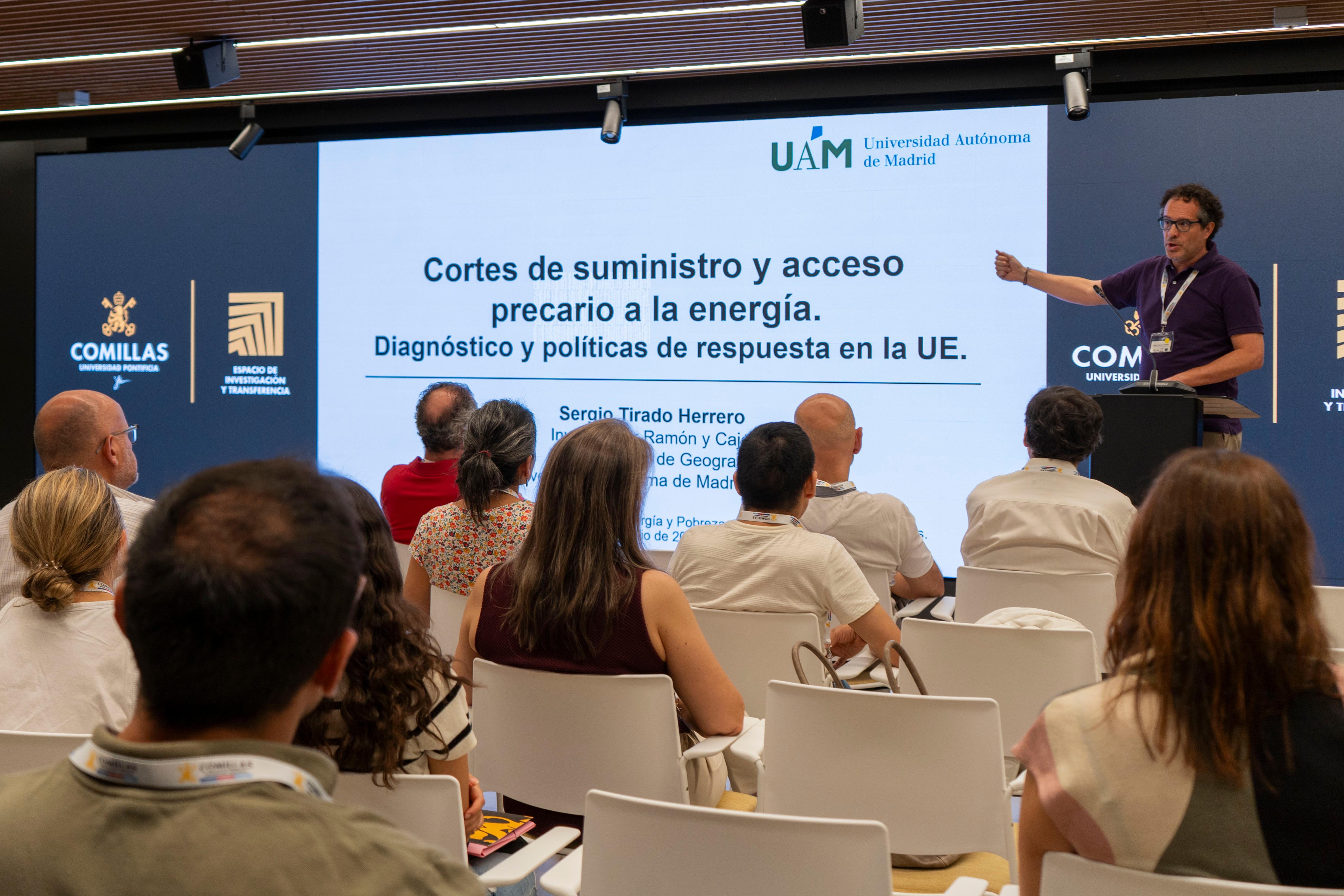 Un ponente presenta un tema sobre cortes de suministro y acceso a la energía ante un público atento en un evento académico.