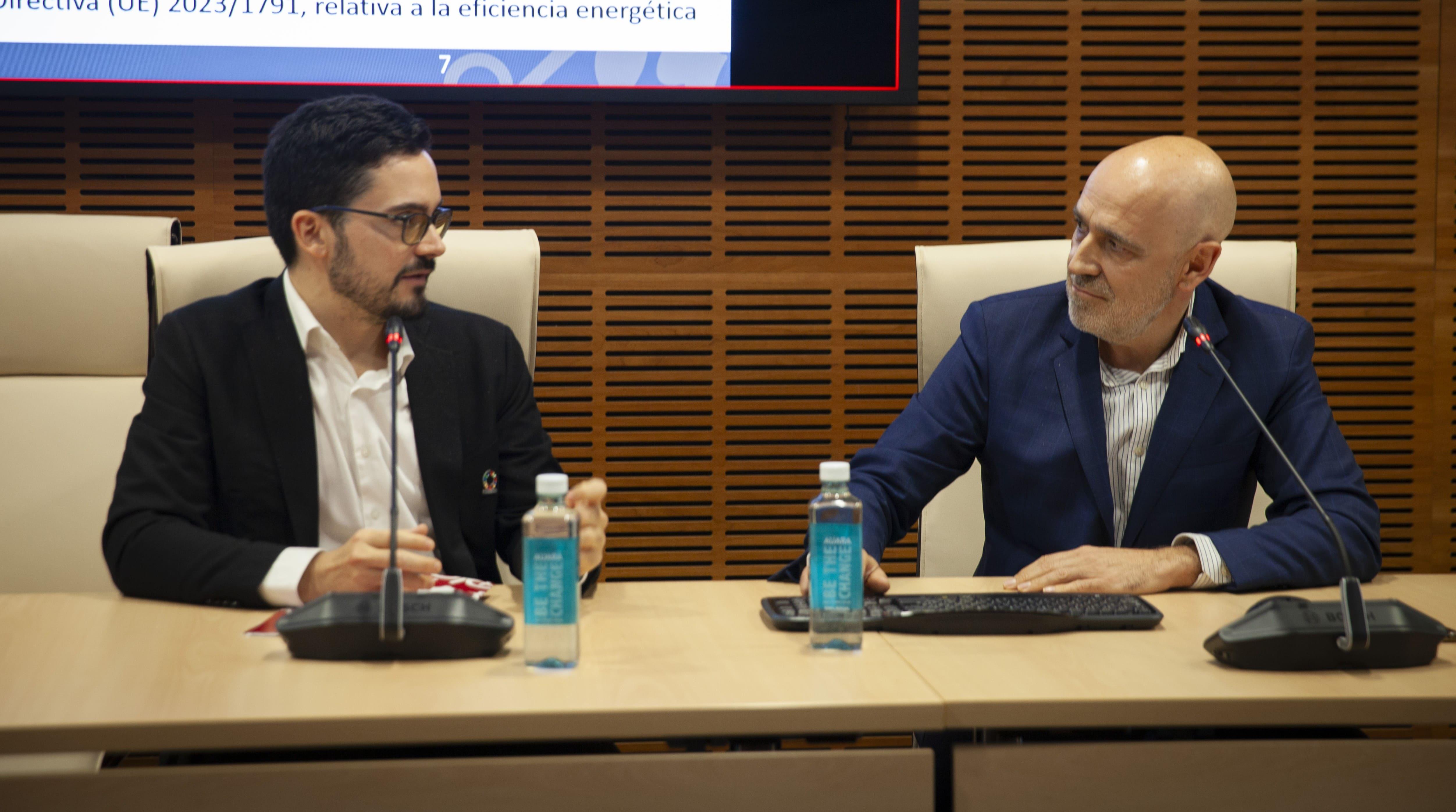 Dos hombres participan en una discusión sobre eficiencia energética en una sala de conferencias.