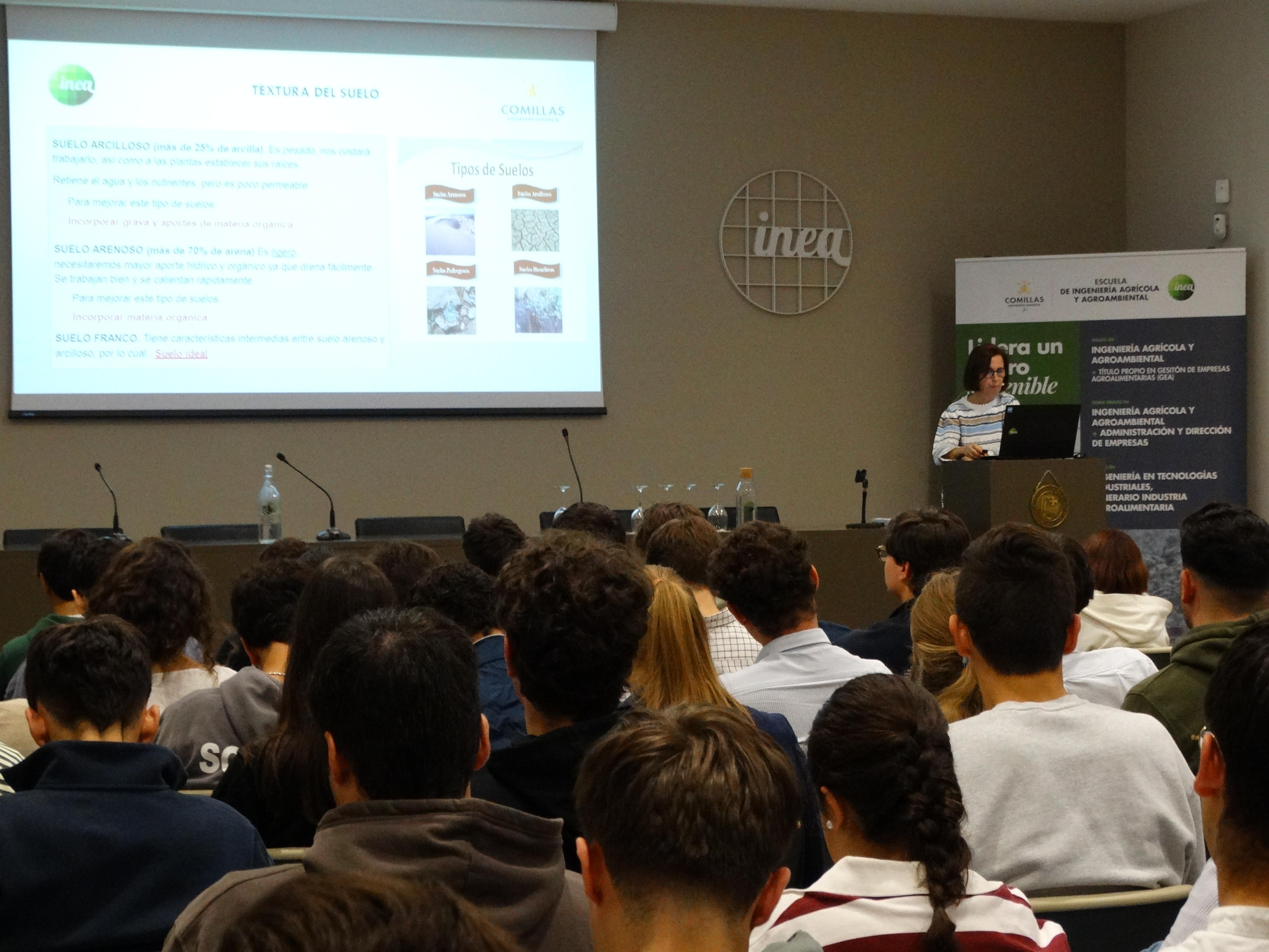 Una presentación en un auditorio donde un ponente se dirige a un grupo de estudiantes atentos.