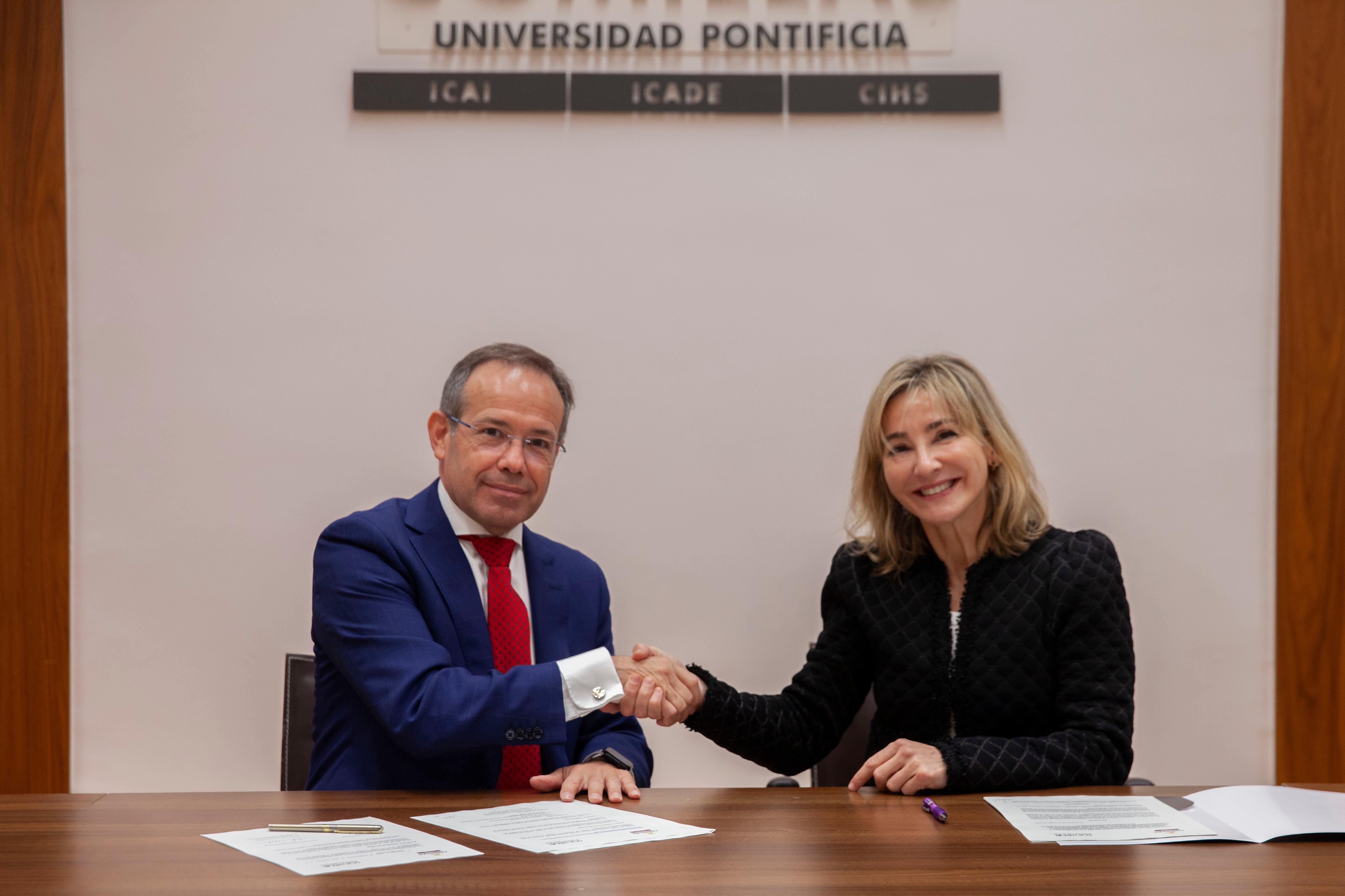 Un hombre y una mujer se estrechan la mano en un acto formal en la Universidad Pontificia.