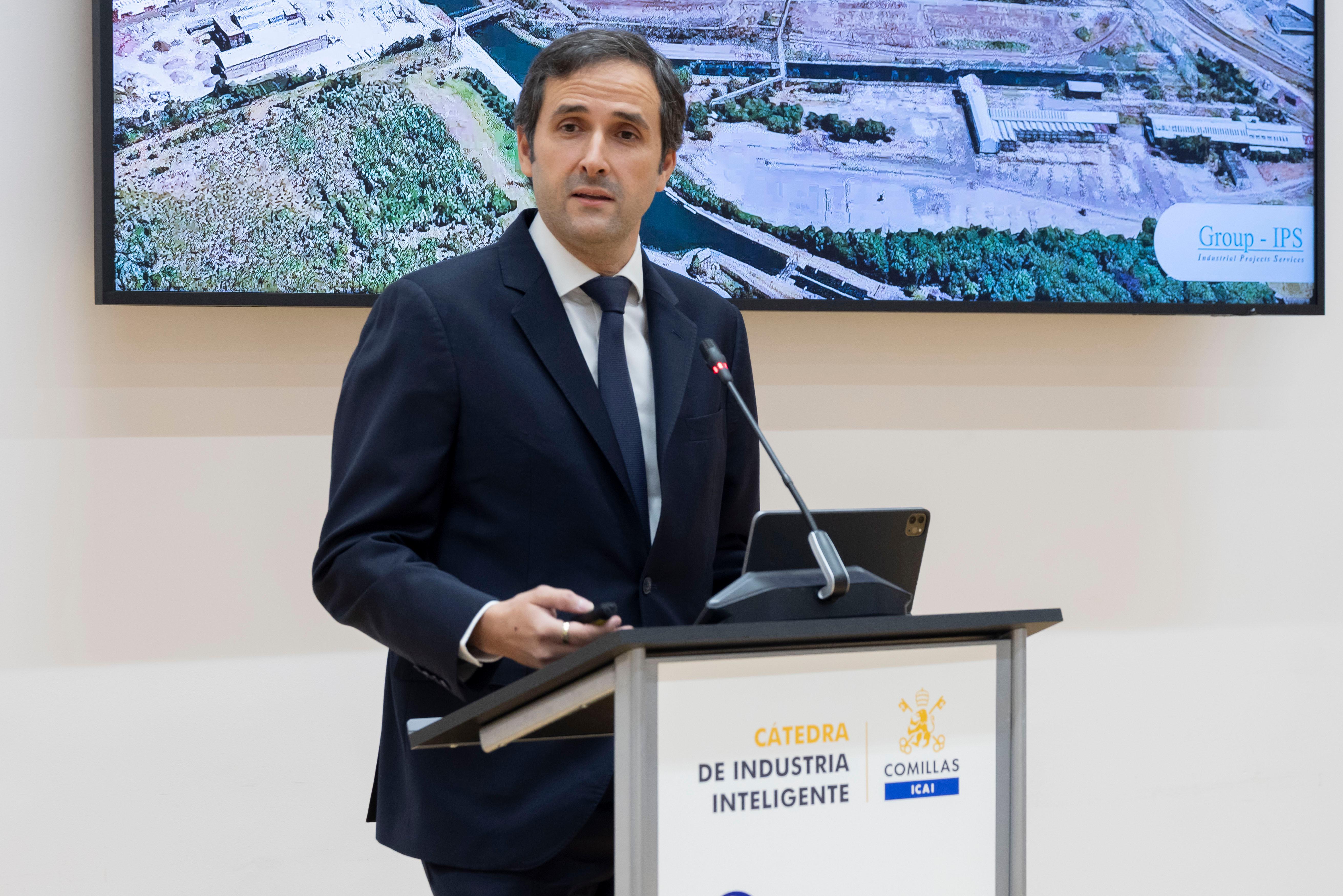 Un hombre de pie presenta información mientras se proyecta una imagen en una pantalla detrás de él.
