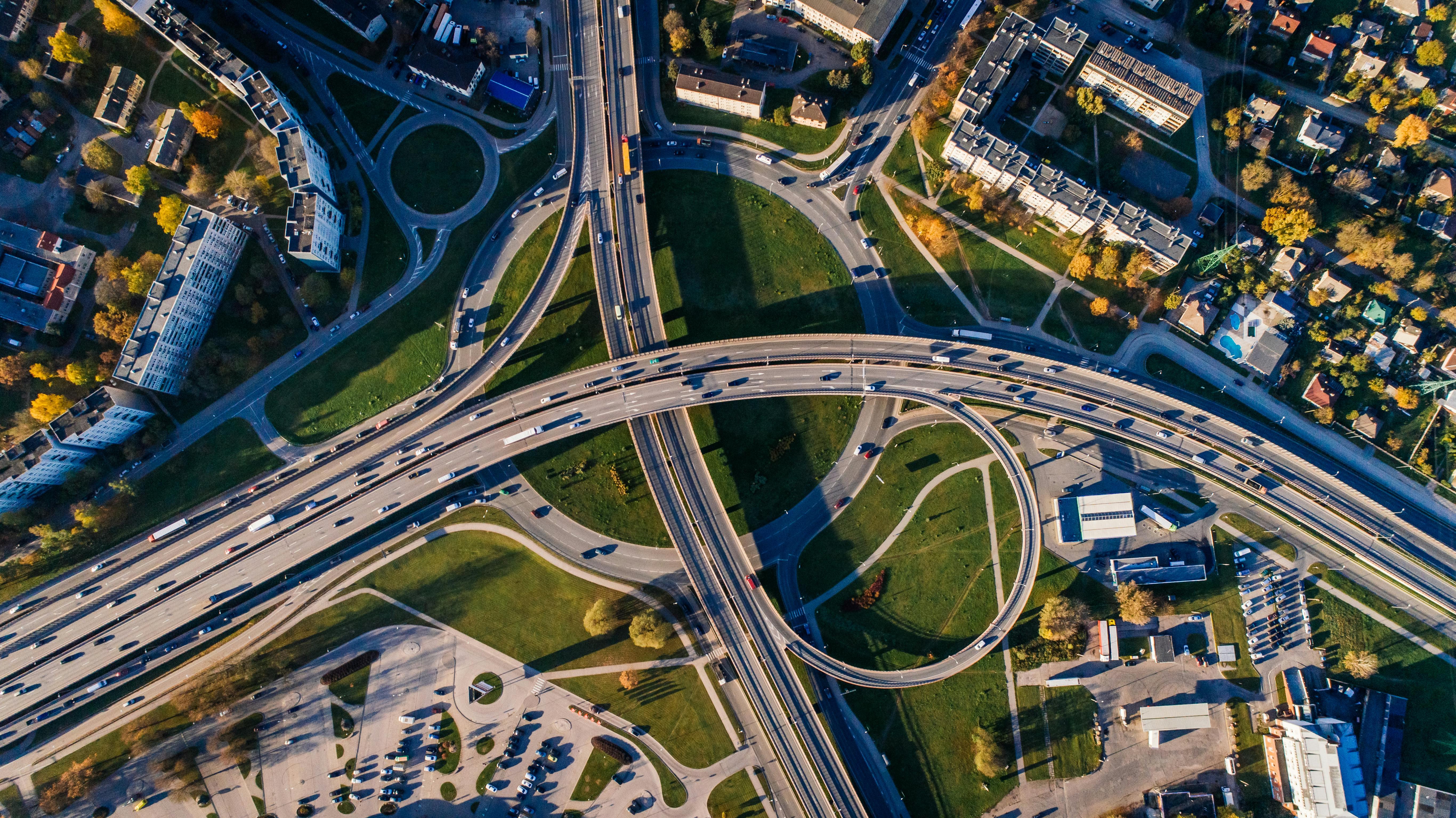 Vista aérea de una intersección de carreteras con múltiples carriles y áreas verdes circundantes en un día soleado.