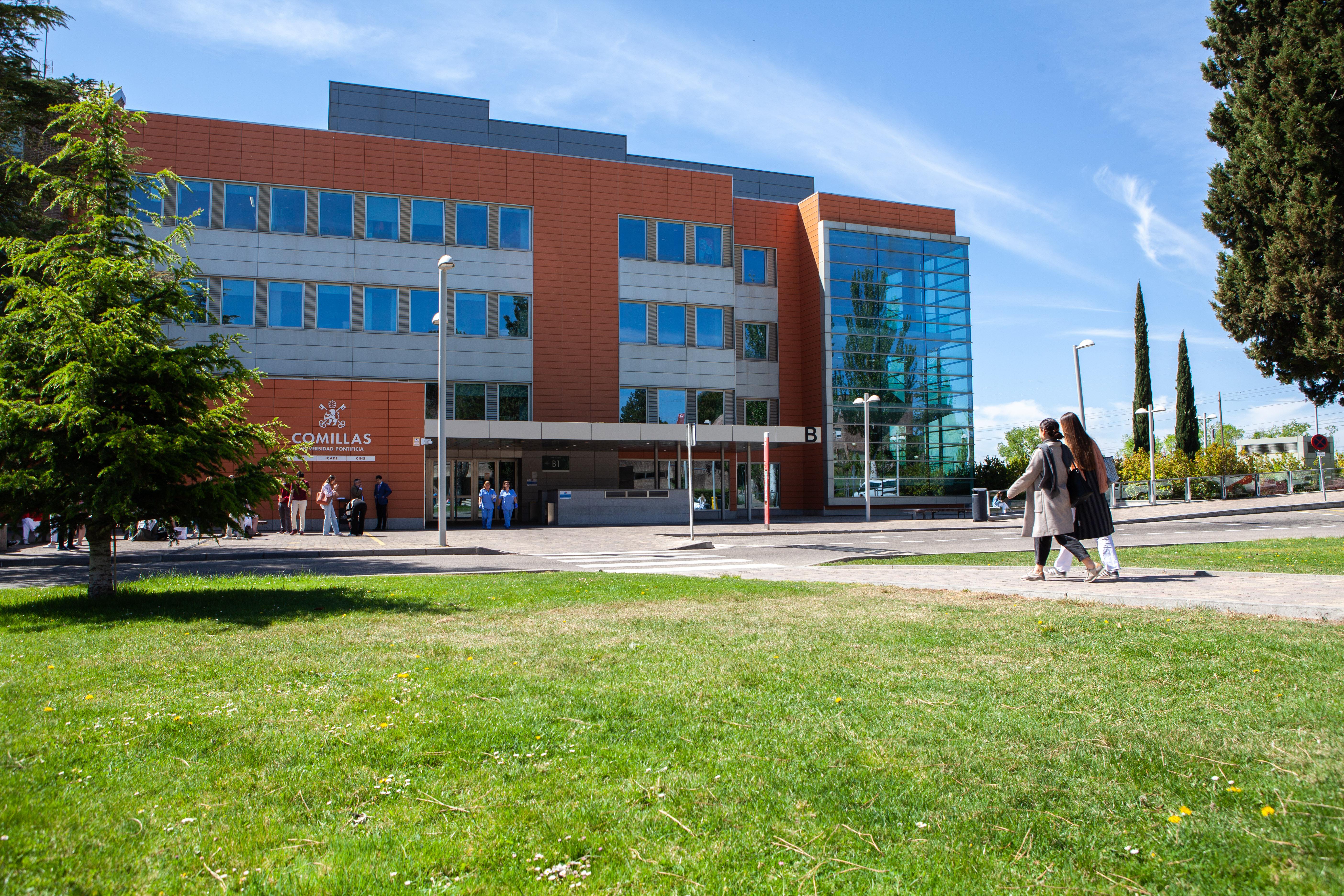 Edificio moderno situado en un campus con personas caminando por el área verde.