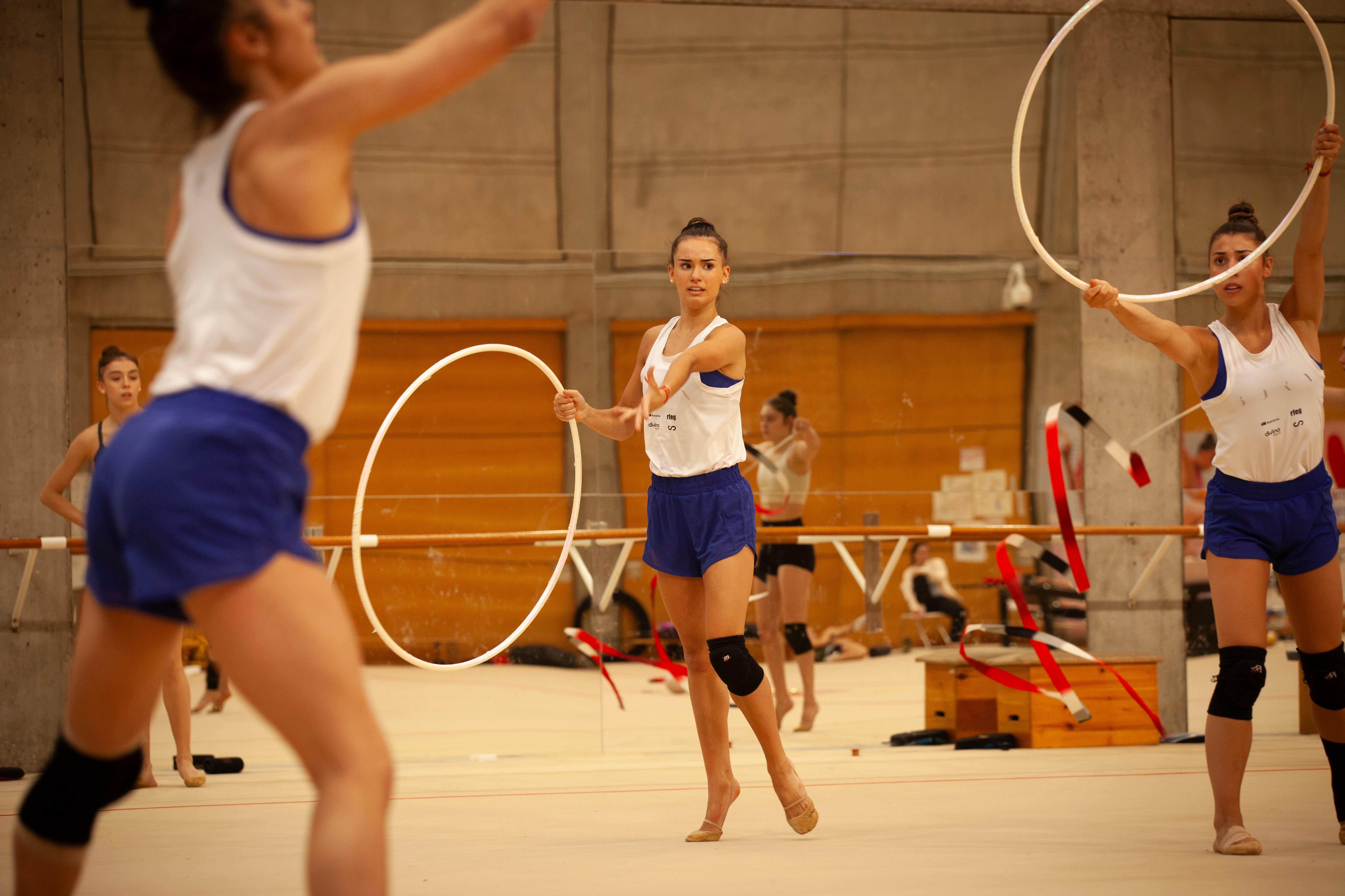 Un grupo de gimnastas realizan ejercicios con aros en un gimnasio.
