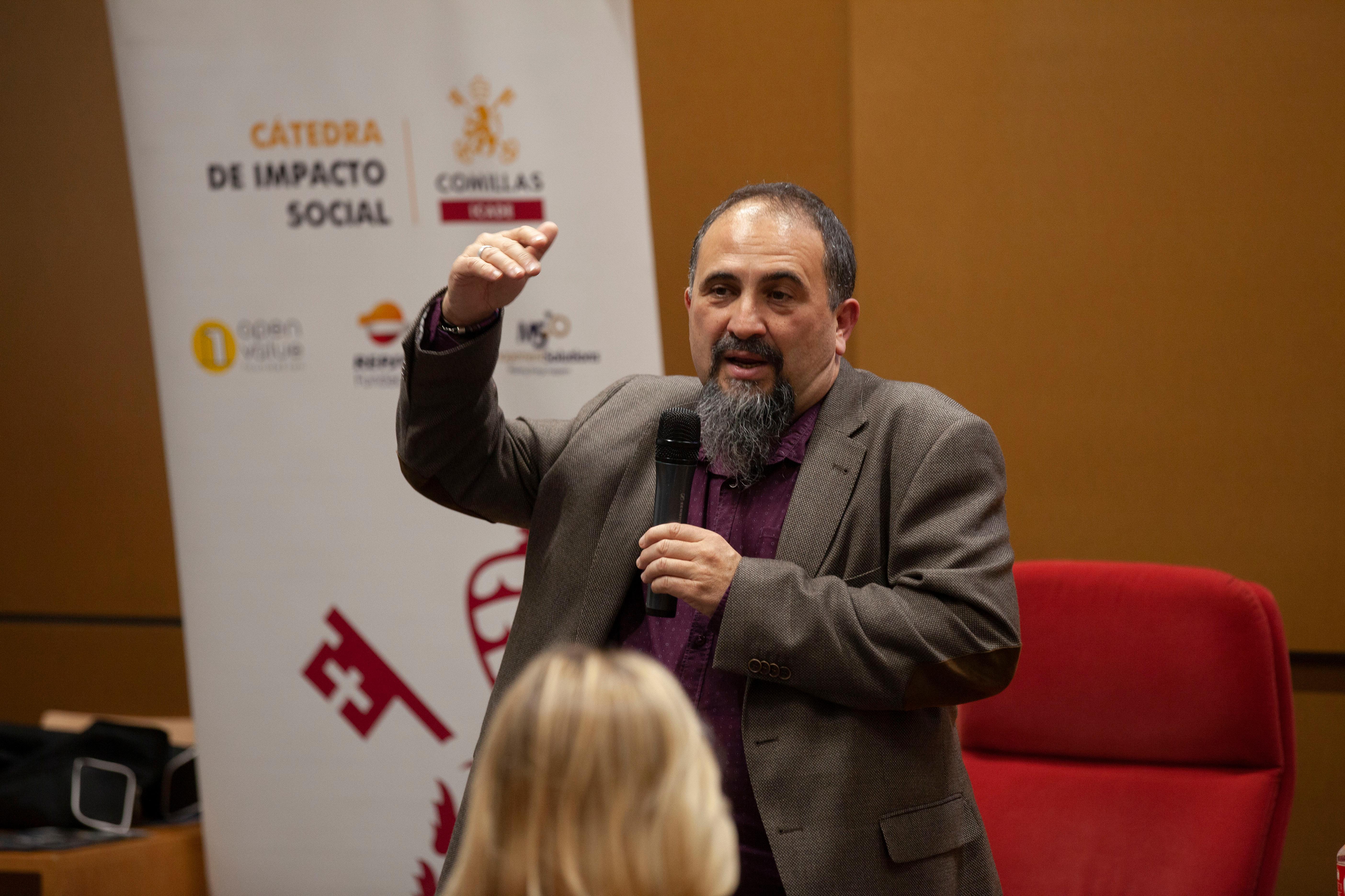 Un hombre hablando con un micrófono en una conferencia frente a un público.