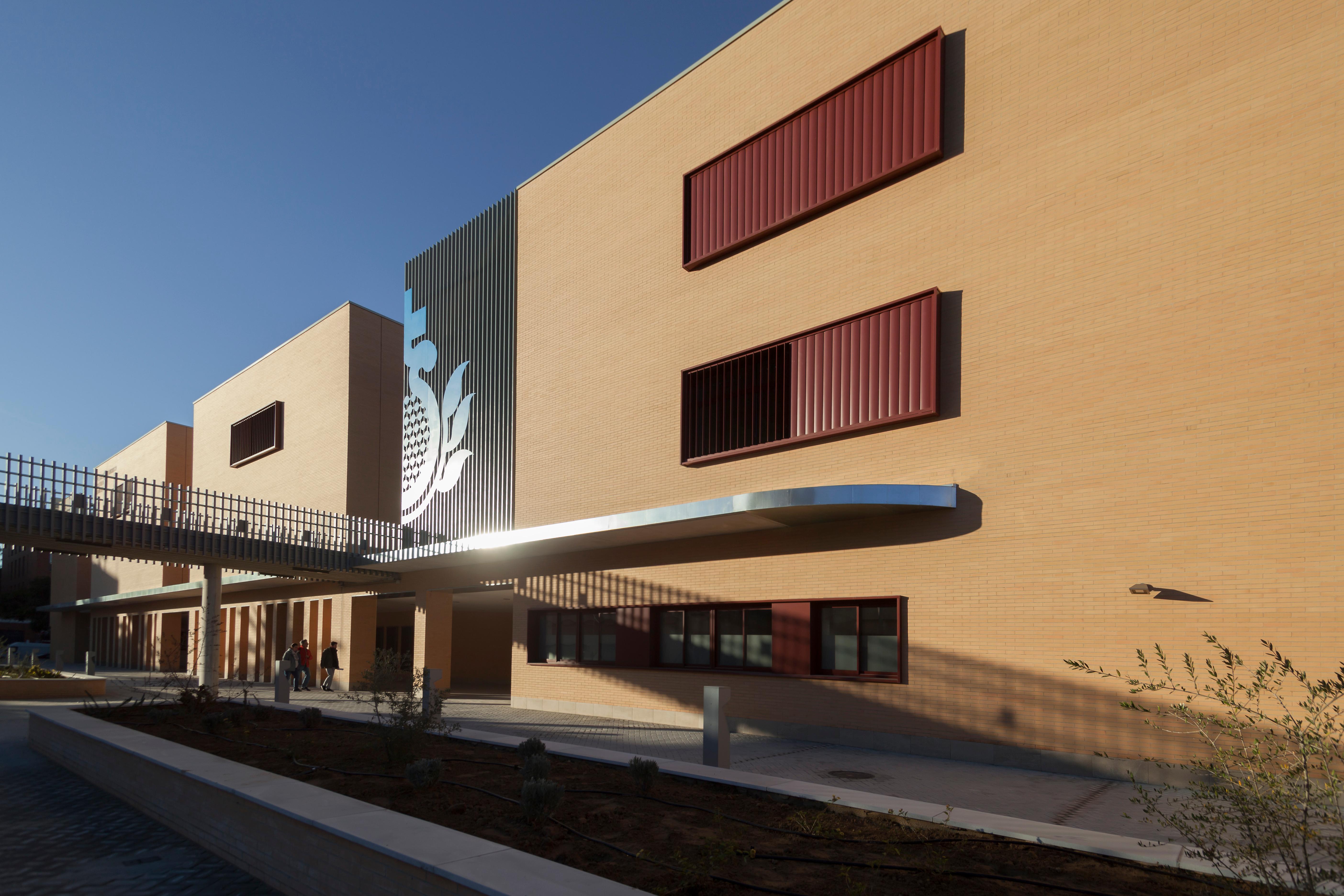 Modern educational building with a yellow facade and large windows under a clear sky.