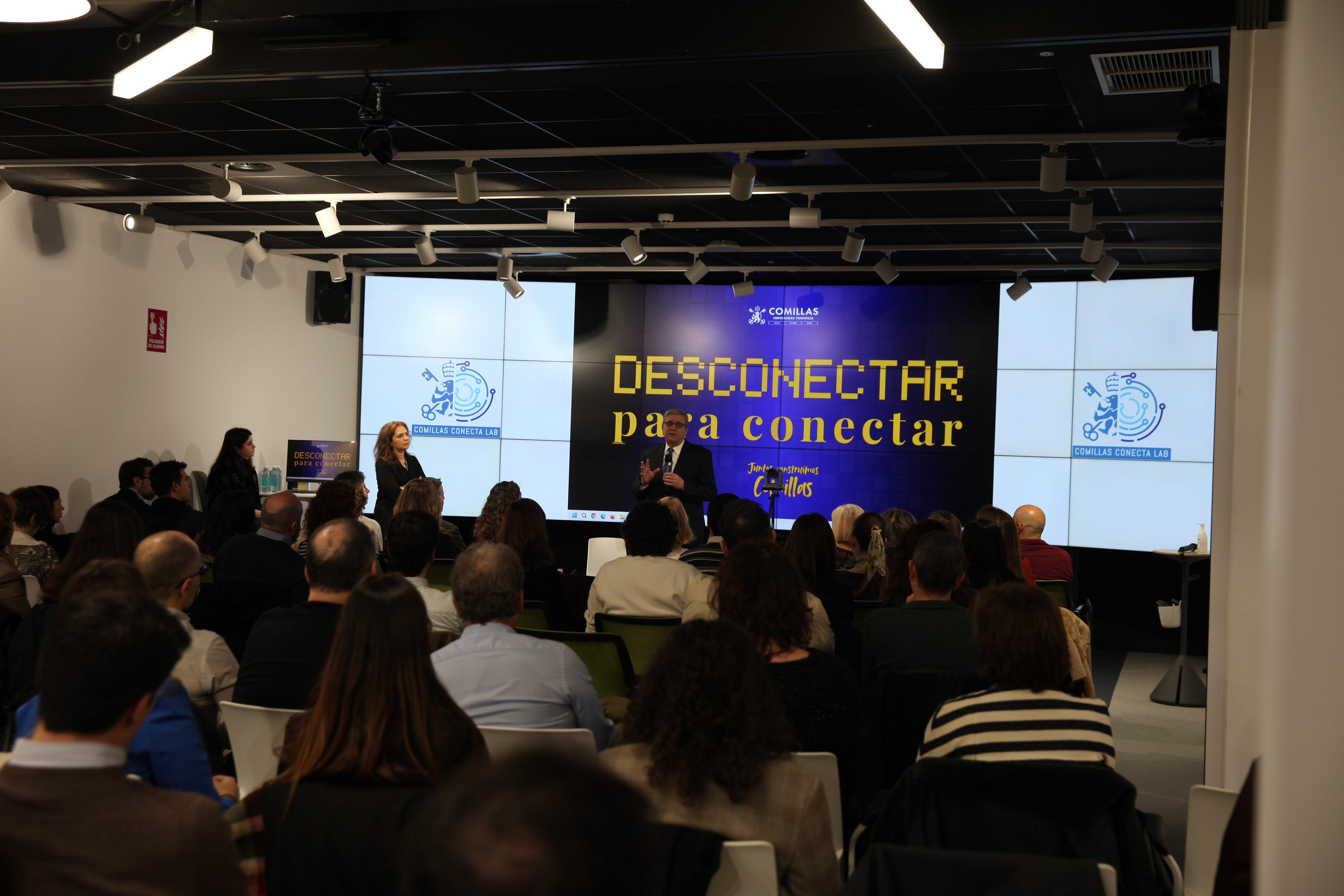 Una conferencia con el tema 'Desconectar para conectar' se lleva a cabo en un salón moderno y lleno de asistentes.