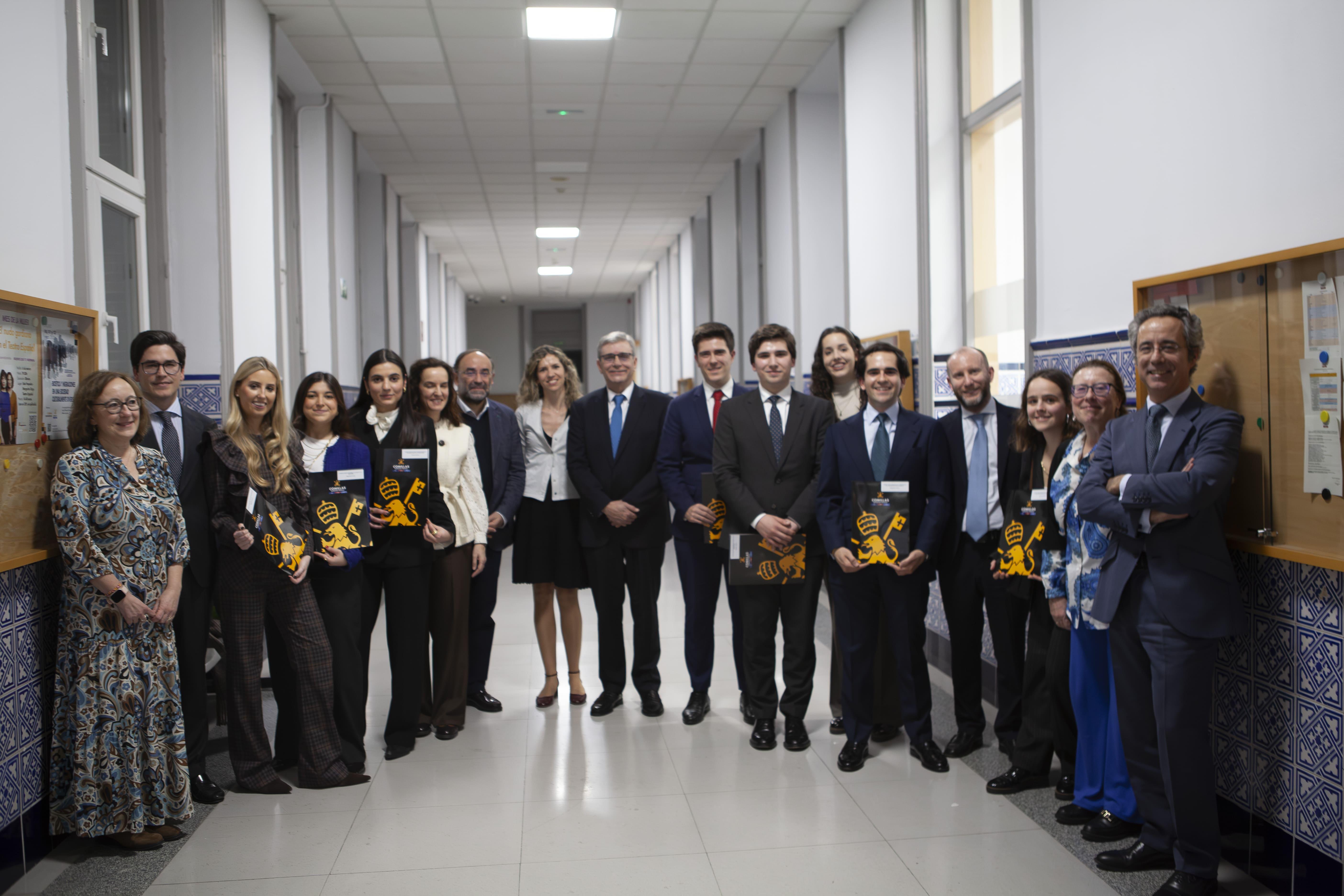 Un grupo de personas se encuentra en un pasillo posando para la foto, algunas sosteniendo carpetas y todos vestidos formalmente.