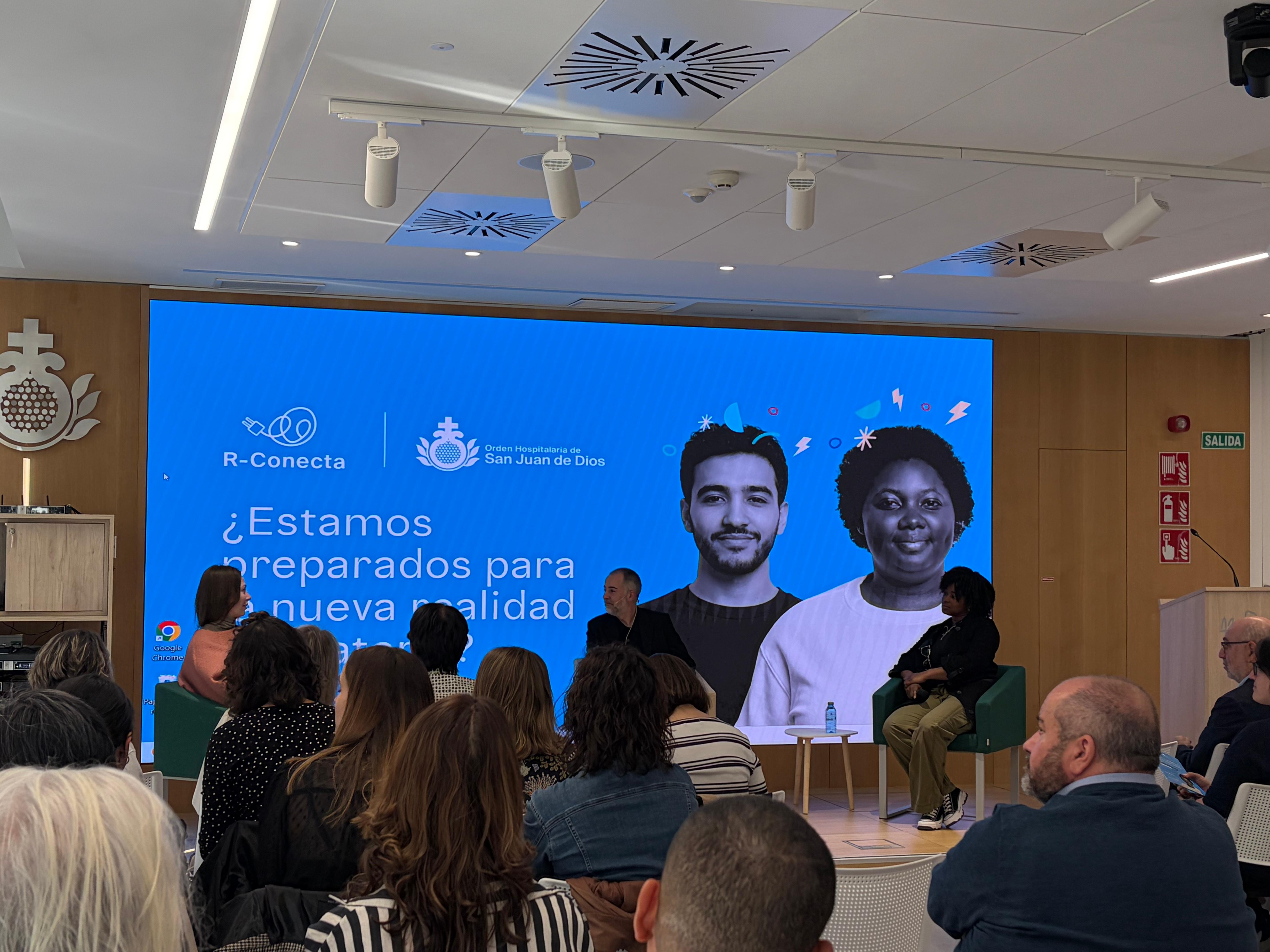 Una conferencia sobre la preparación para una nueva calidad, con dos ponentes en el escenario y un público atento.