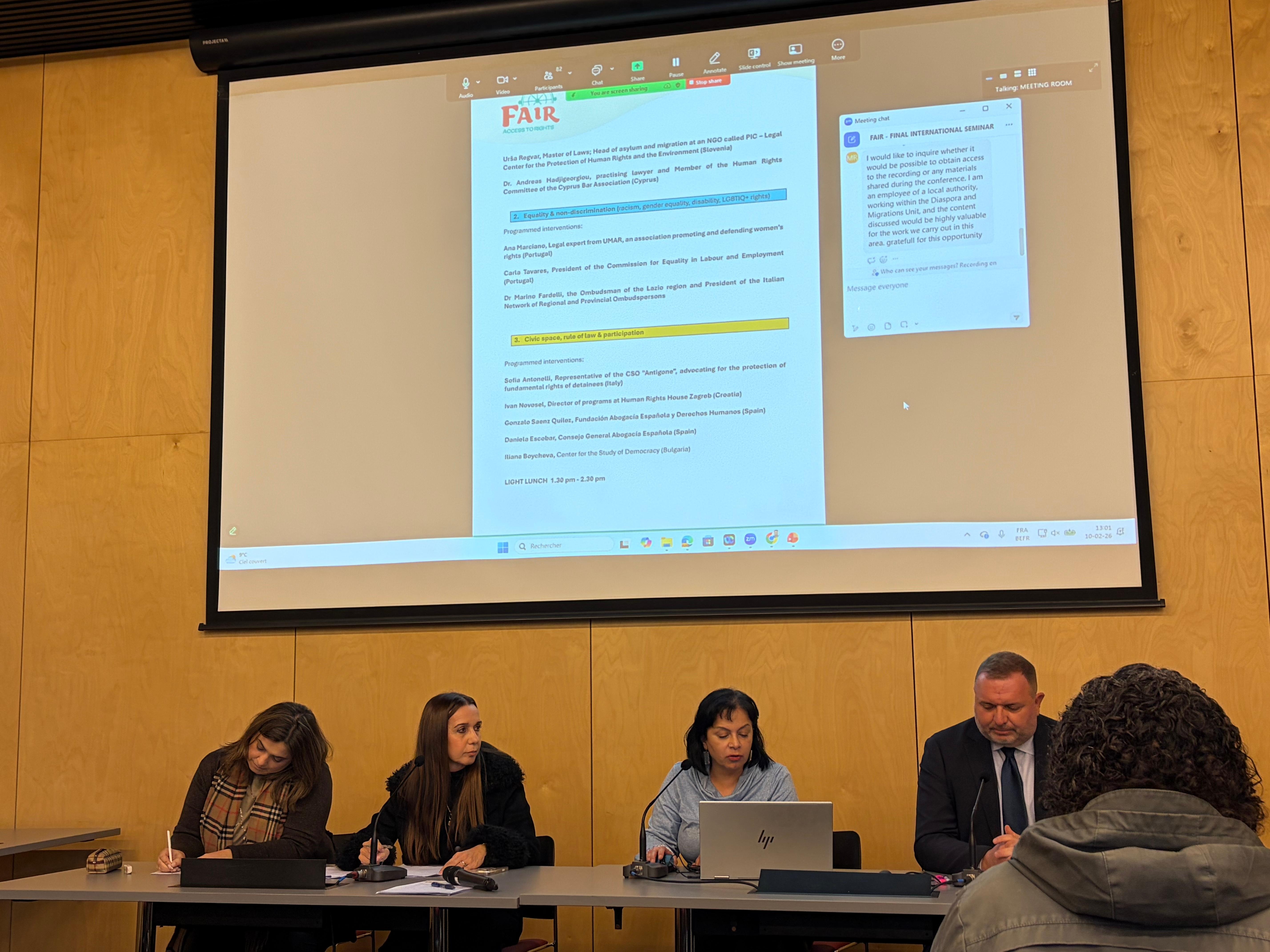 Reunión de varias personas discutiendo en una sala con una presentación en pantalla.