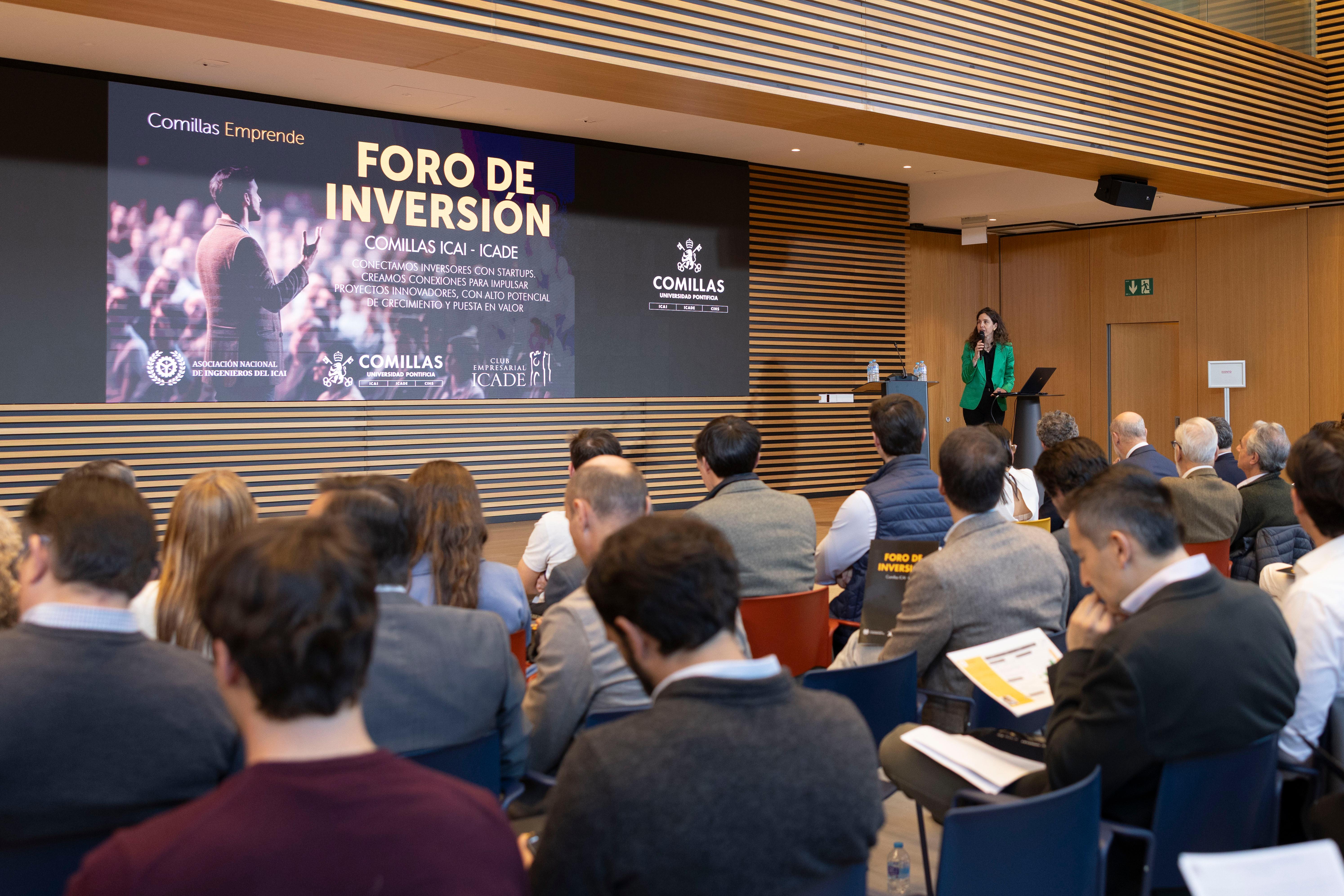 La imagen muestra un foro de inversión con un ponente en el escenario y una audiencia atenta.