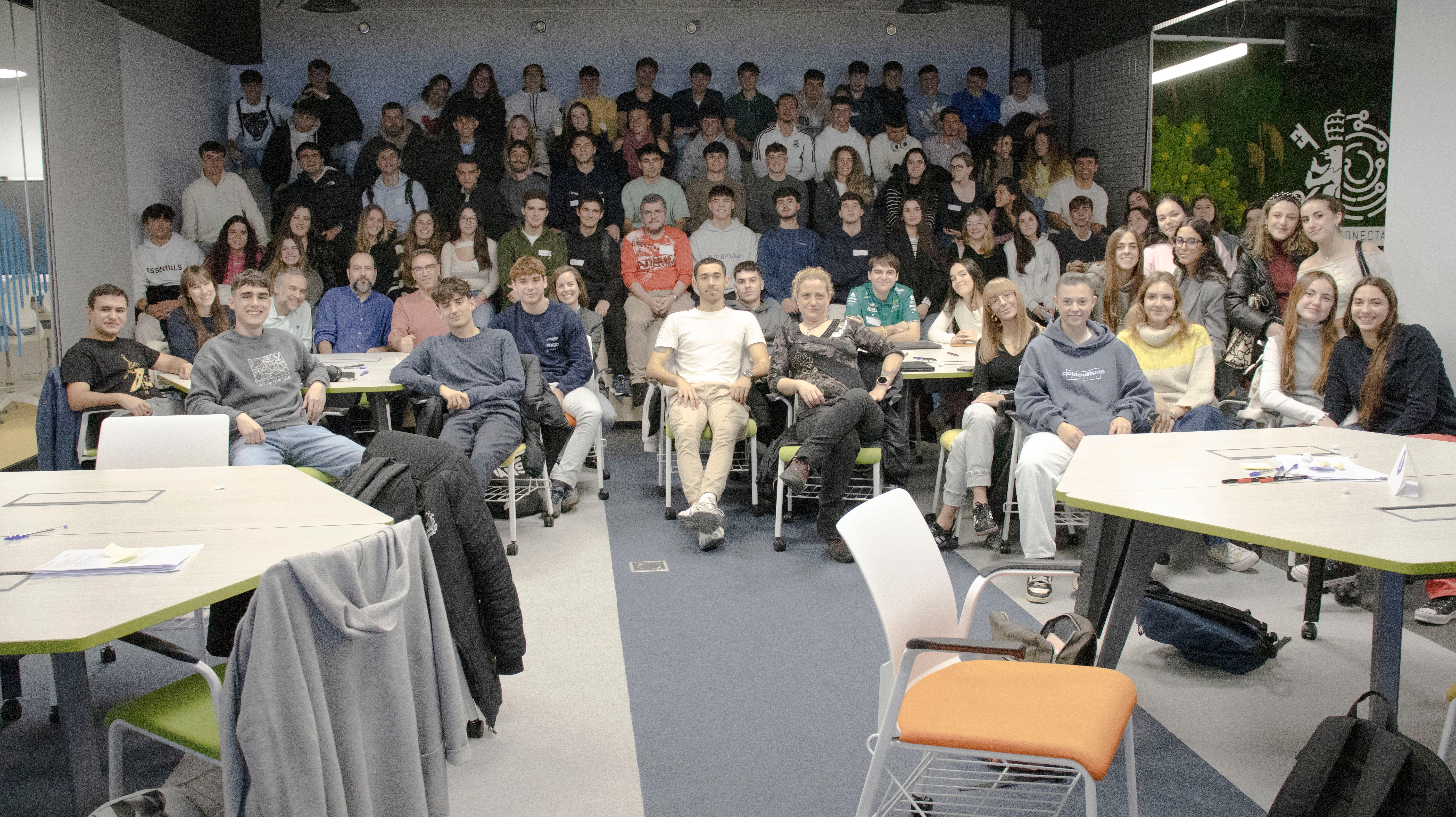 Un grupo grande de personas, probablemente estudiantes, posa para una foto en un aula moderna.