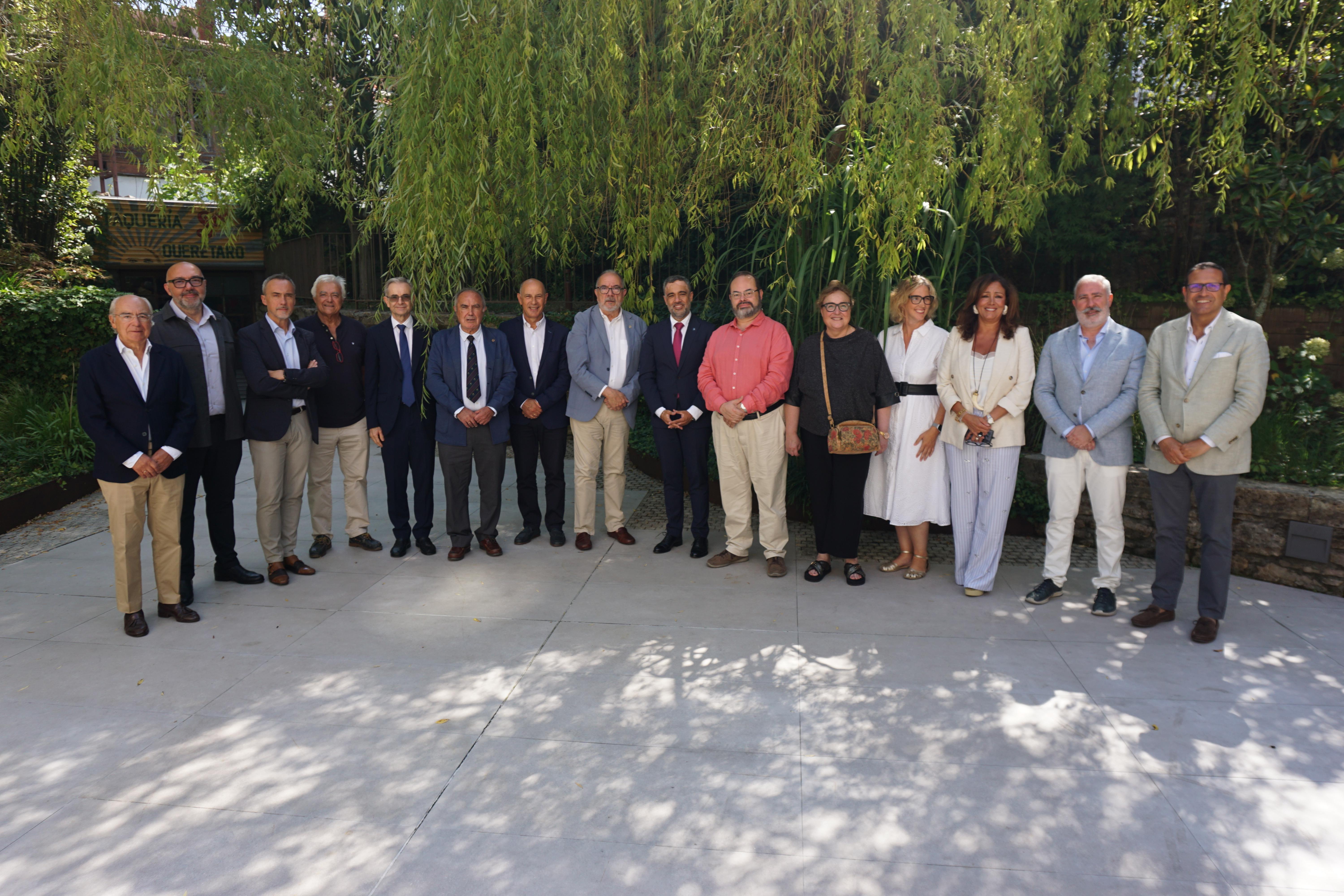 Grupo de personas posando al aire libre con un fondo verde.