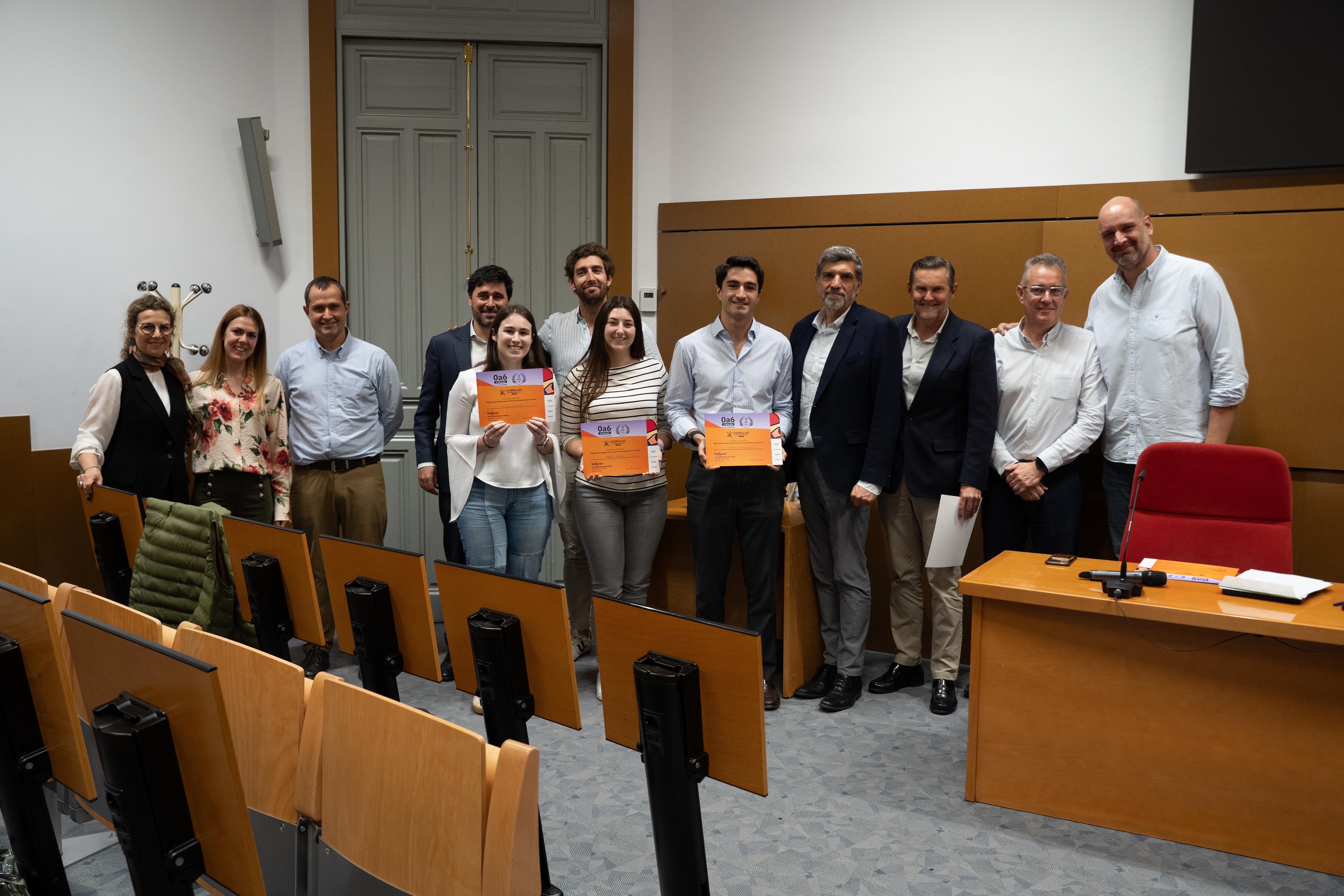 Un grupo de personas posando en una sala después de un evento, sosteniendo certificados.