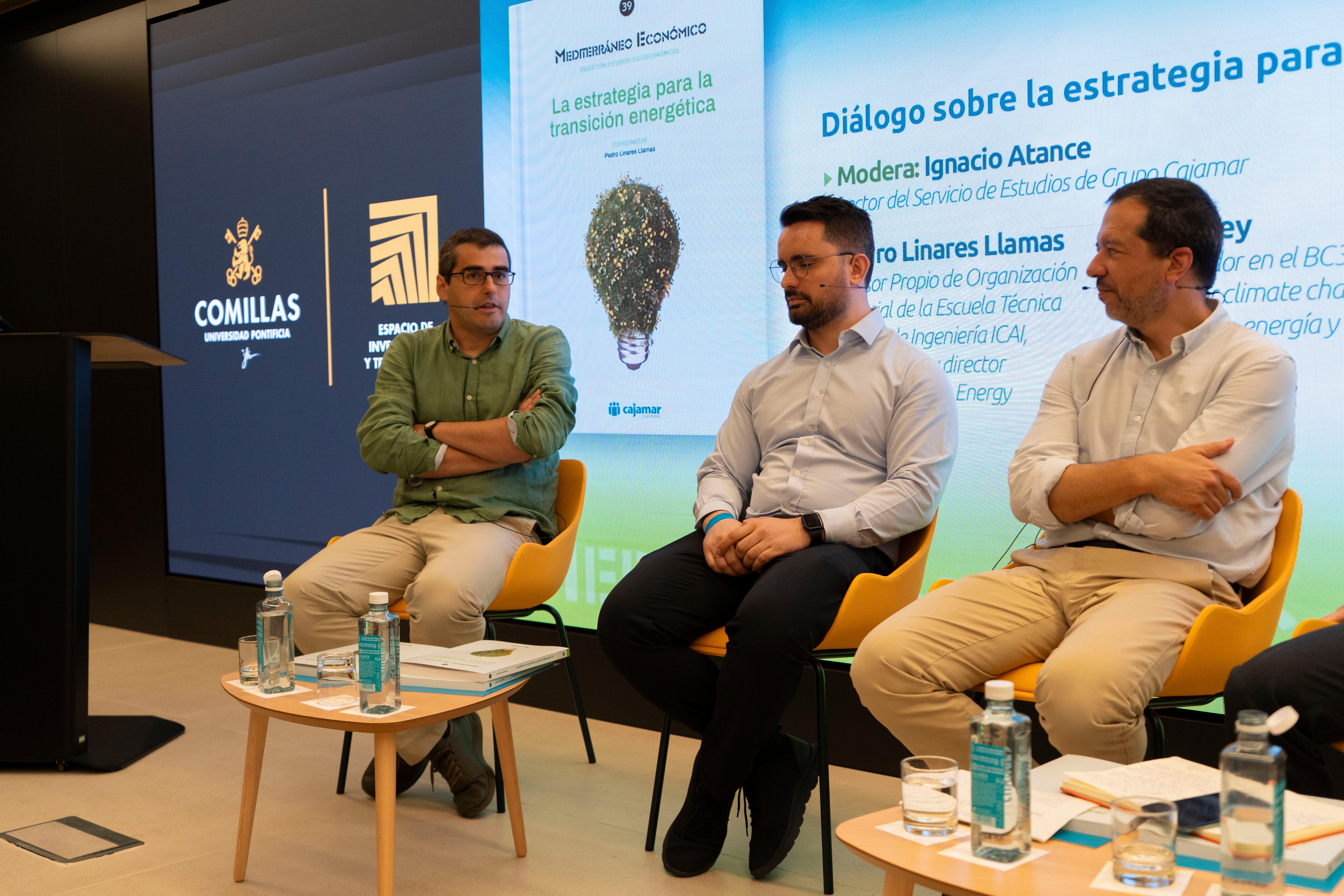 Imagen de un panel de discusión sobre la transición energética con tres oradores sentados frente a una audiencia.
